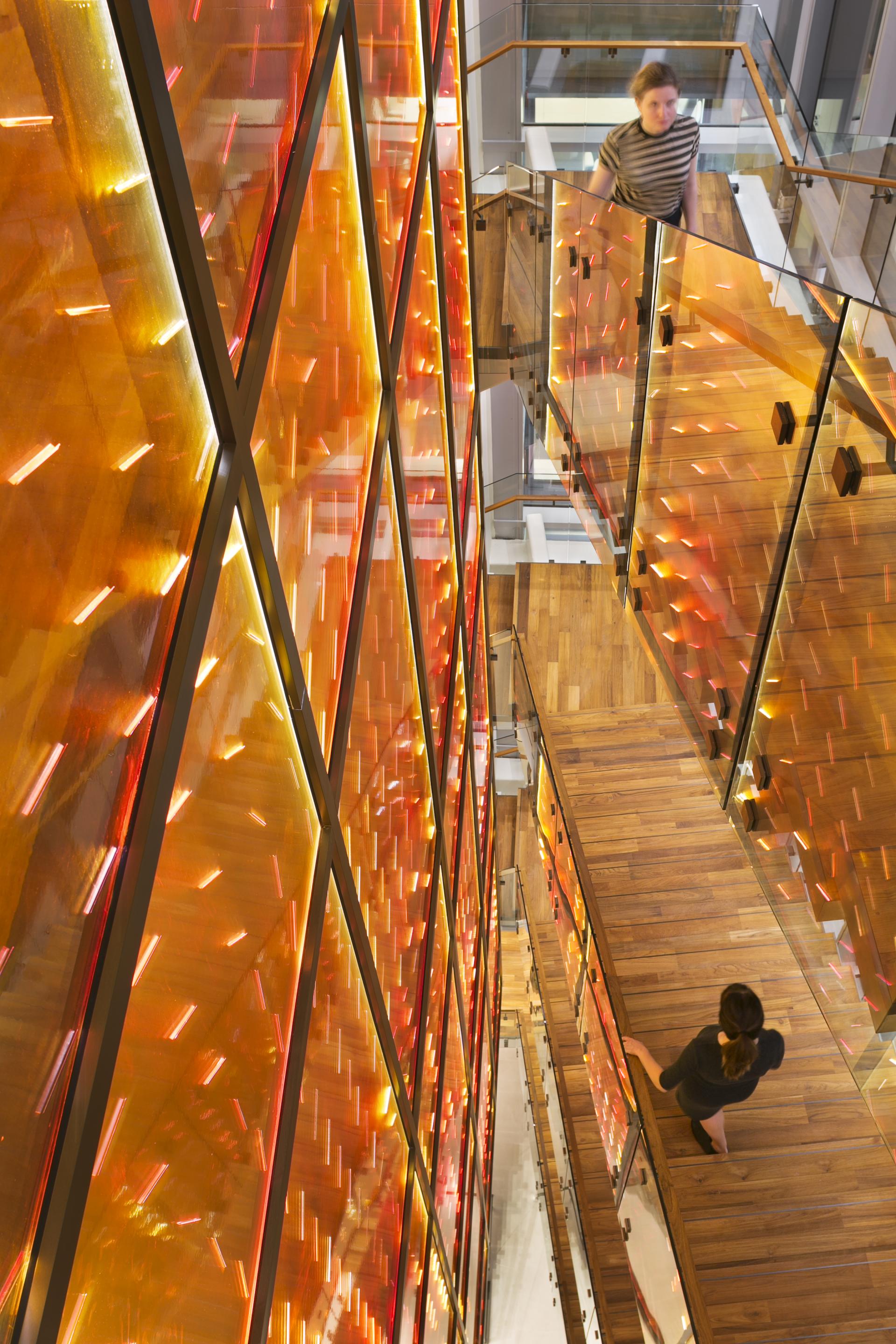 Dynamic illuminated architecture featuring warm orange hues and innovative materials, highlighting sustainability and aesthetic design.