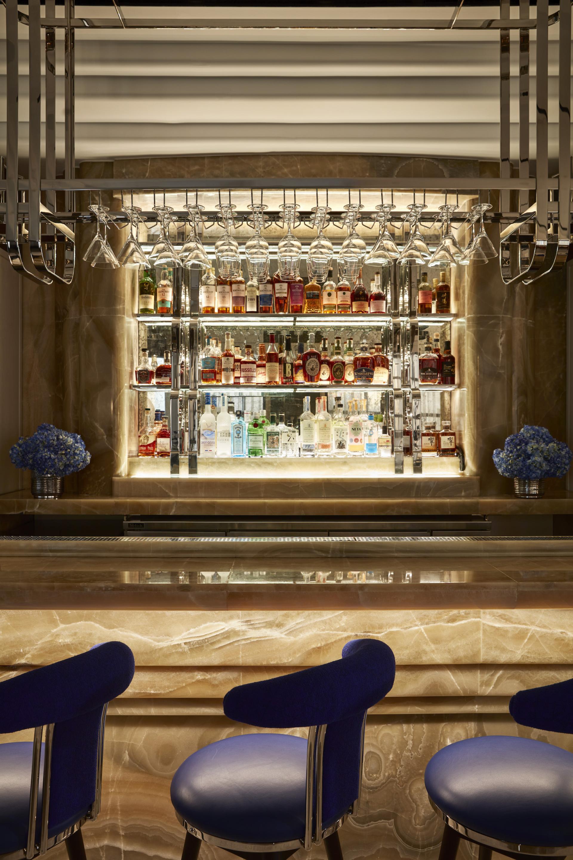 Elegant bar area featuring a sophisticated collection of spirits, Art Deco-inspired design, and plush seating.