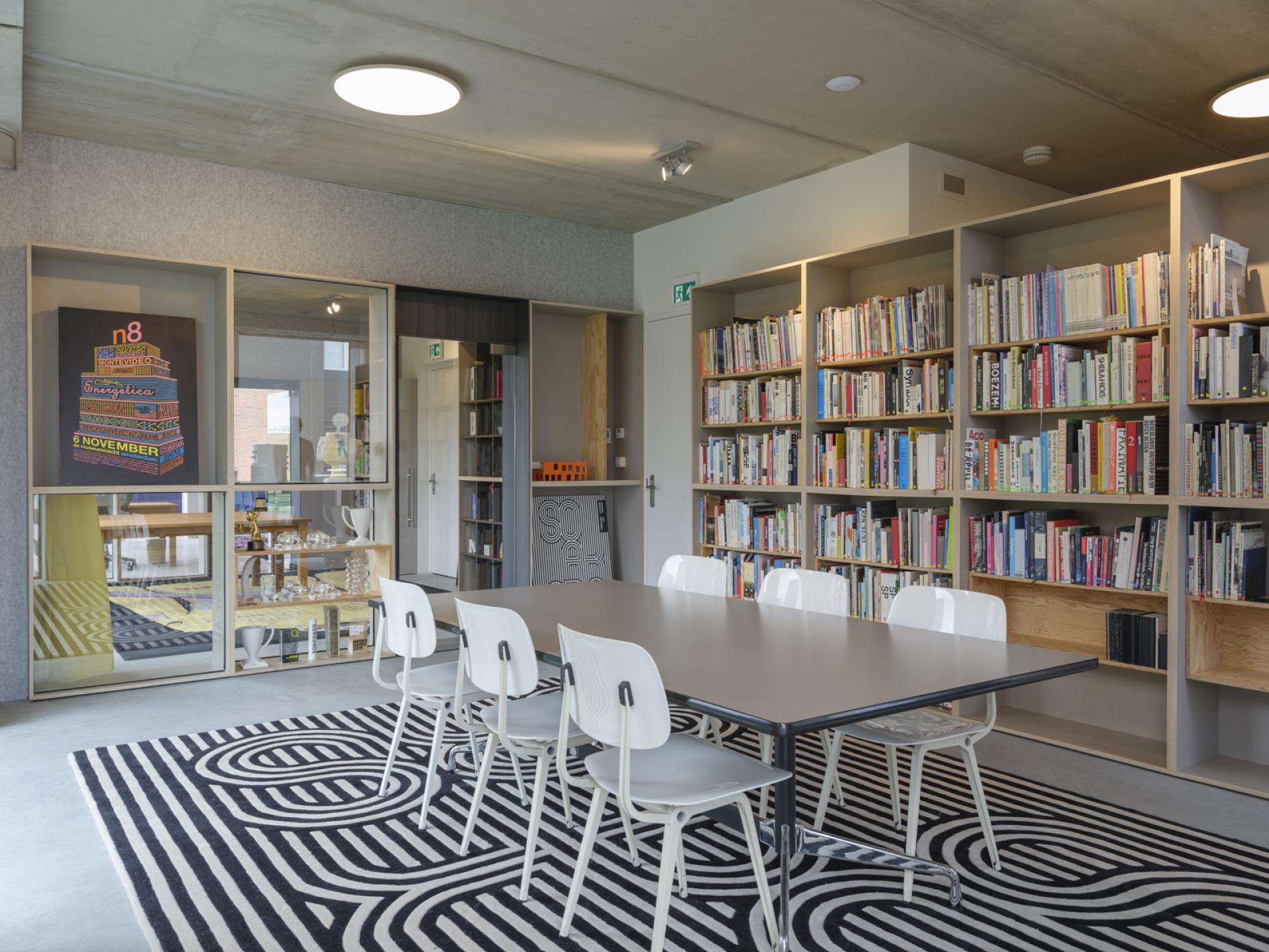Modern studio interior of thonik, featuring a collaborative workspace, bookshelves, and artistic rugs in Amsterdam.
