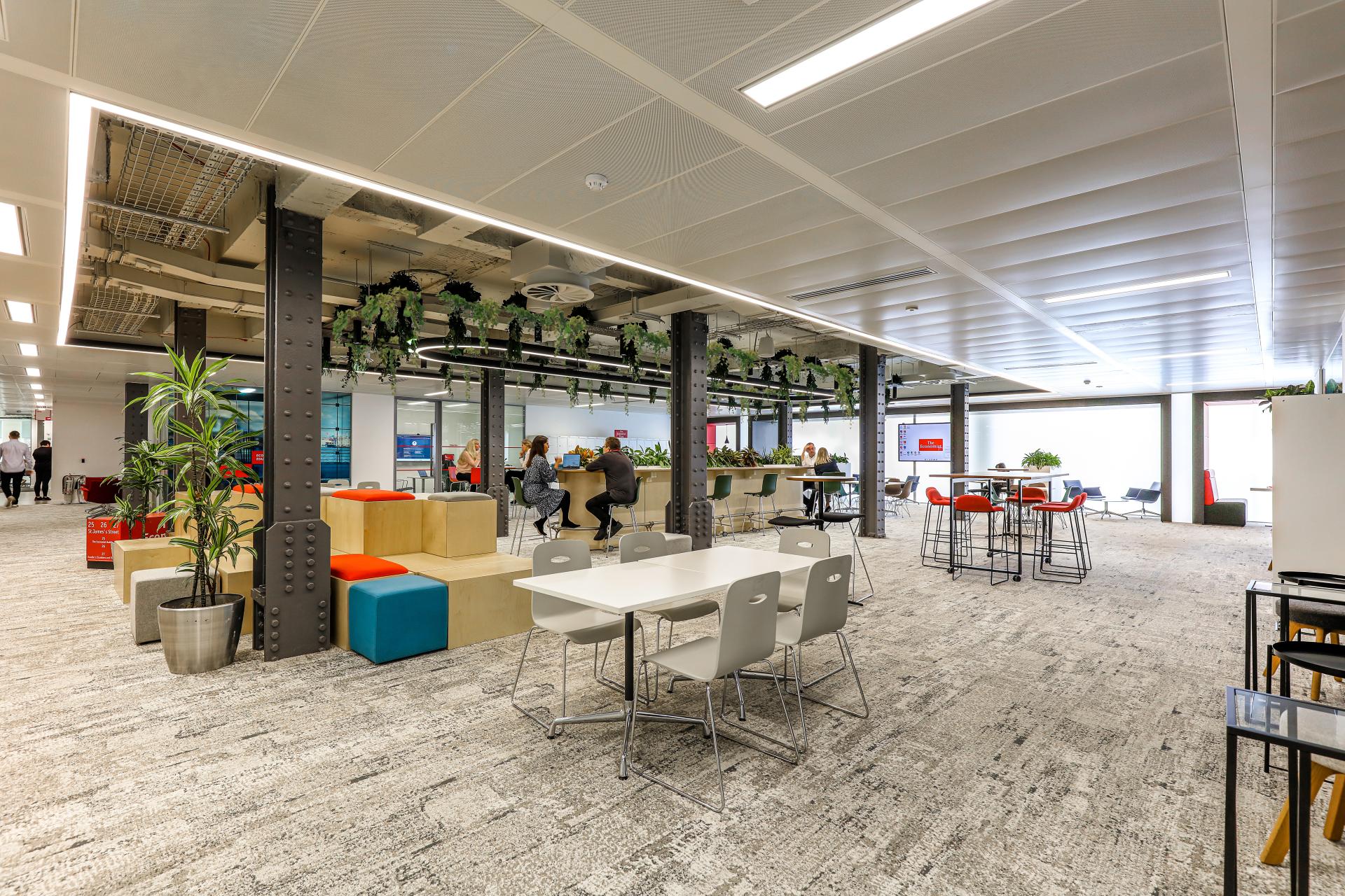 Modern office space featuring collaborative work areas, sustainable design elements, and greenery for The Economist Group's new workplace.