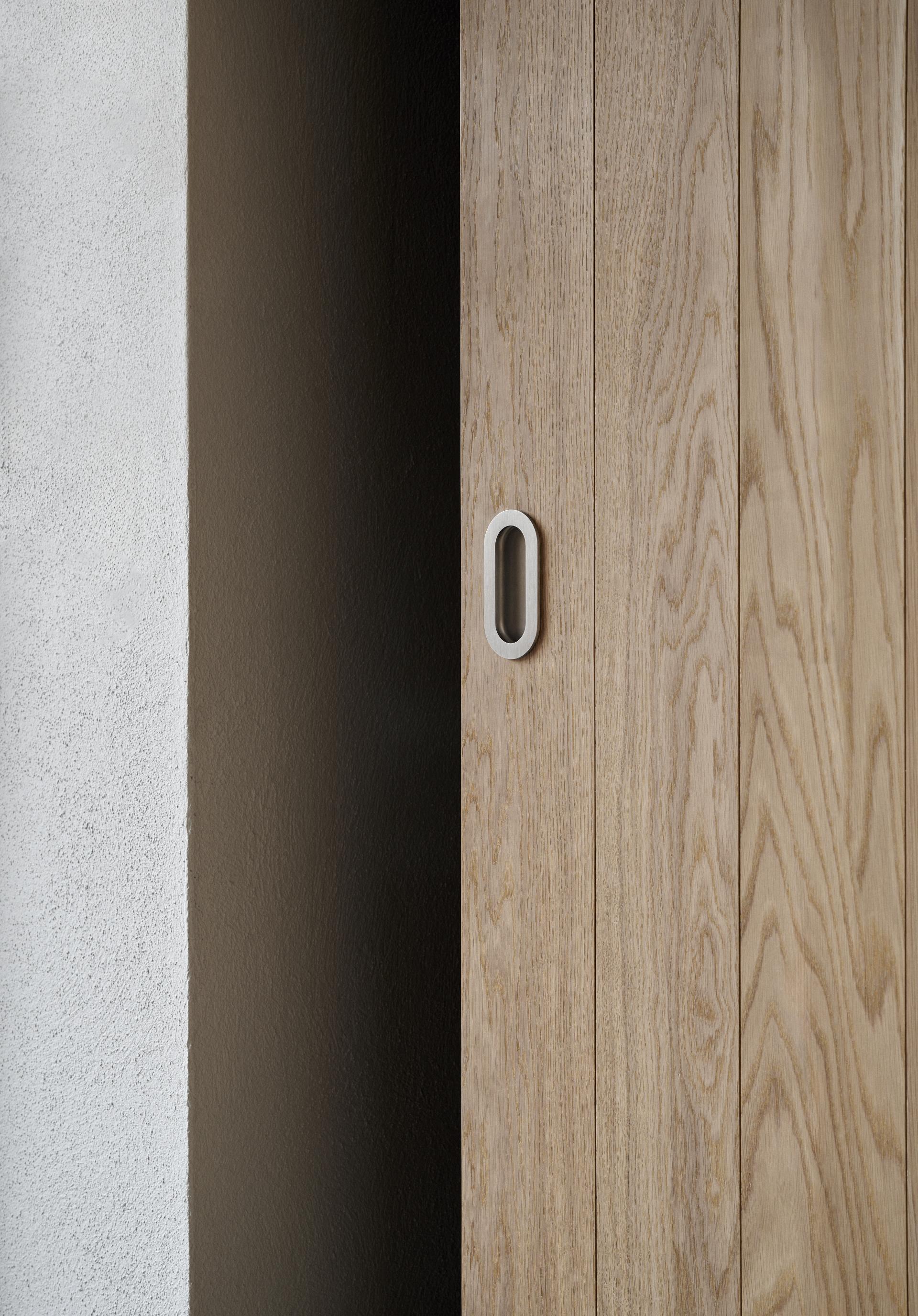 Elegant wood paneling with a modern handle, showcasing Scandinavian design aesthetics in a minimalist interior setting.