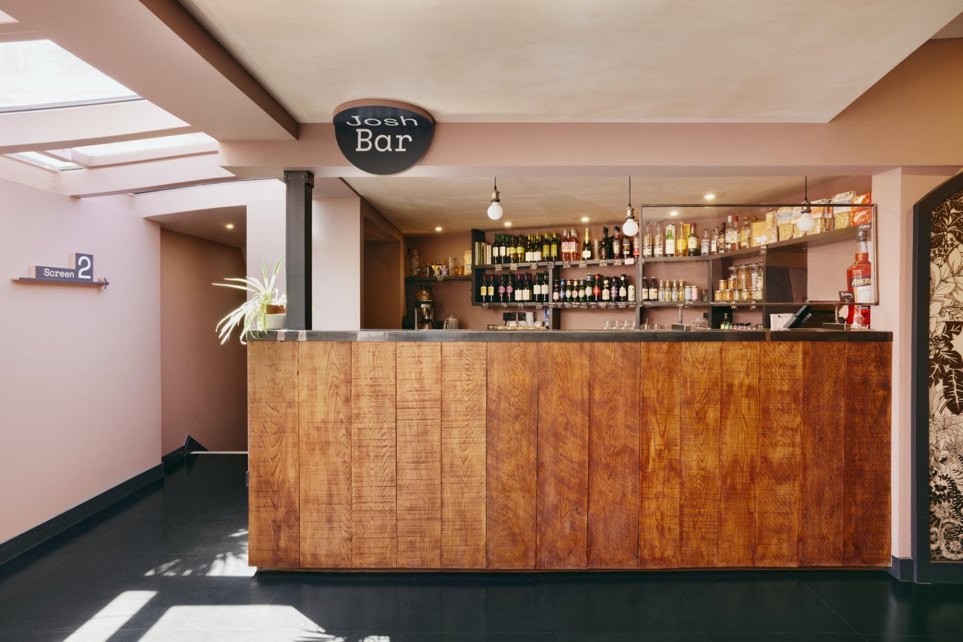 Modern bar area at The Lexi cinema, showcasing a stylish wooden counter and a variety of beverages.
