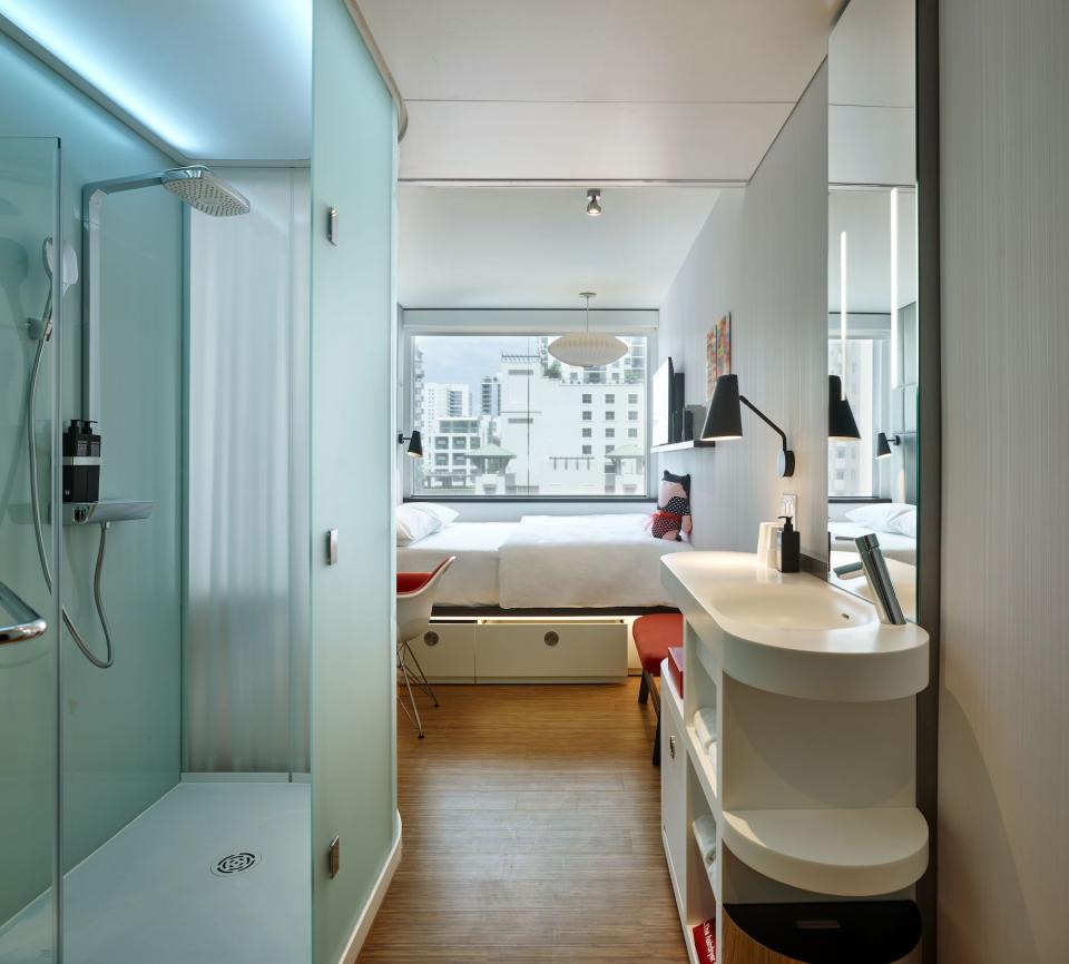 Modern citizenM hotel room in Miami featuring stylish bathroom, workspace, and city views from the large window.
