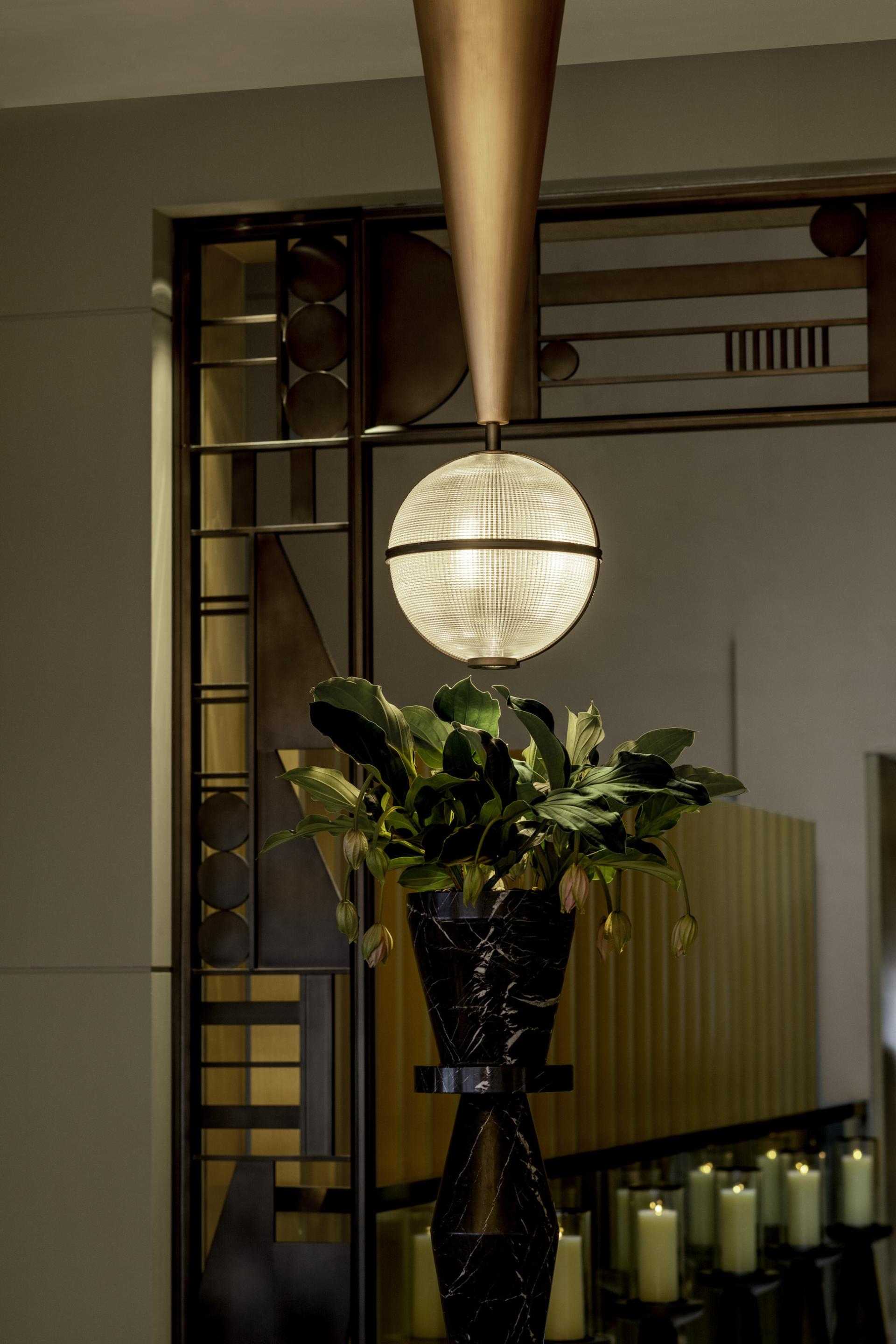 Art Deco lighting fixture and elegant floral arrangement enhance the sophisticated dining atmosphere at The Upper House, Hong Kong.