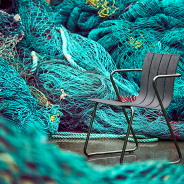 Sleek black chair designed by Jørgen and Nanna Ditzel, set against vibrant fishing nets in the Ocean Collection.