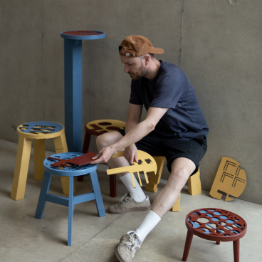 Ewan Crallan assembling colorful, playful furniture designs in a creative workspace, highlighting his unique designer approach.
