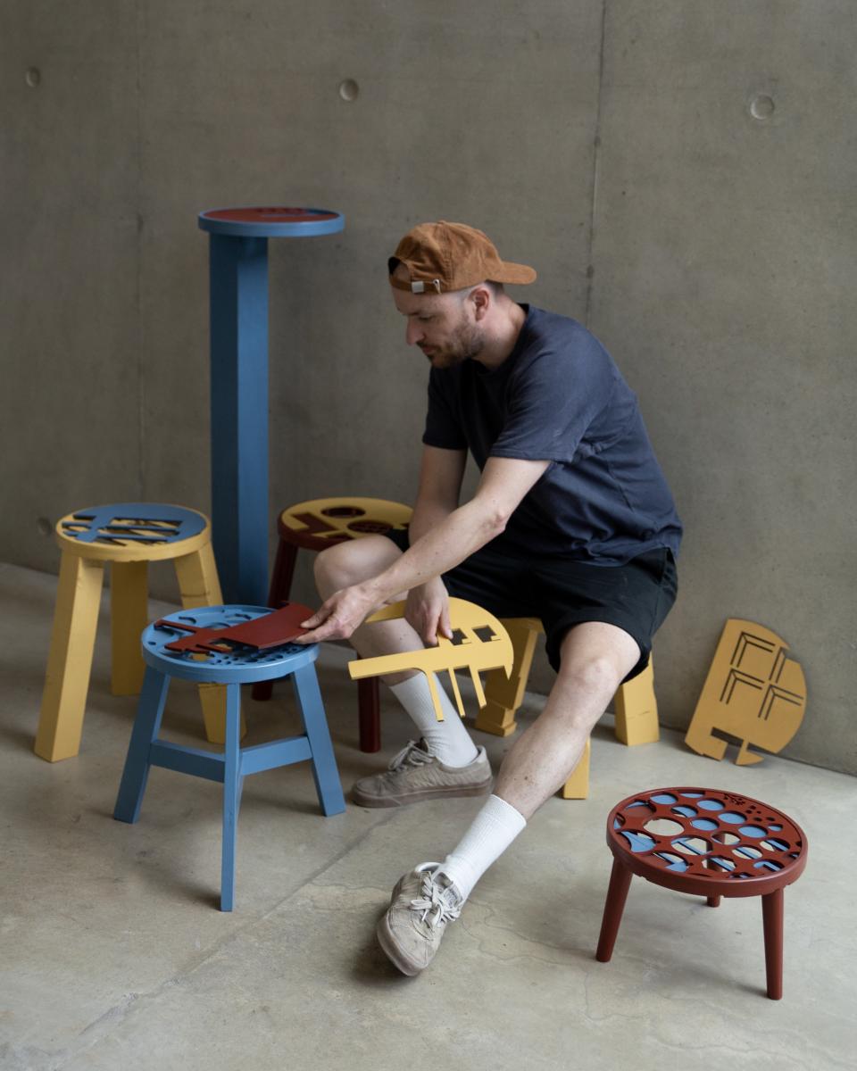 Ewan Crallan assembling colorful, playful furniture designs in a creative workspace, highlighting his unique designer approach.