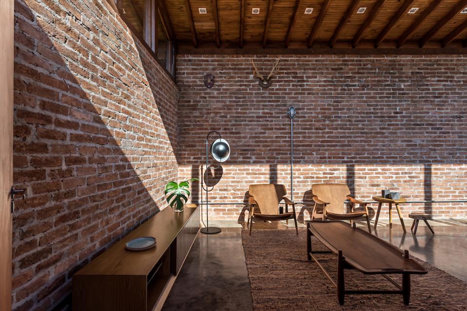 Modern interior of The Lake House featuring exposed brick walls, wooden furniture, and natural light, designed by Solo Arquitetos.