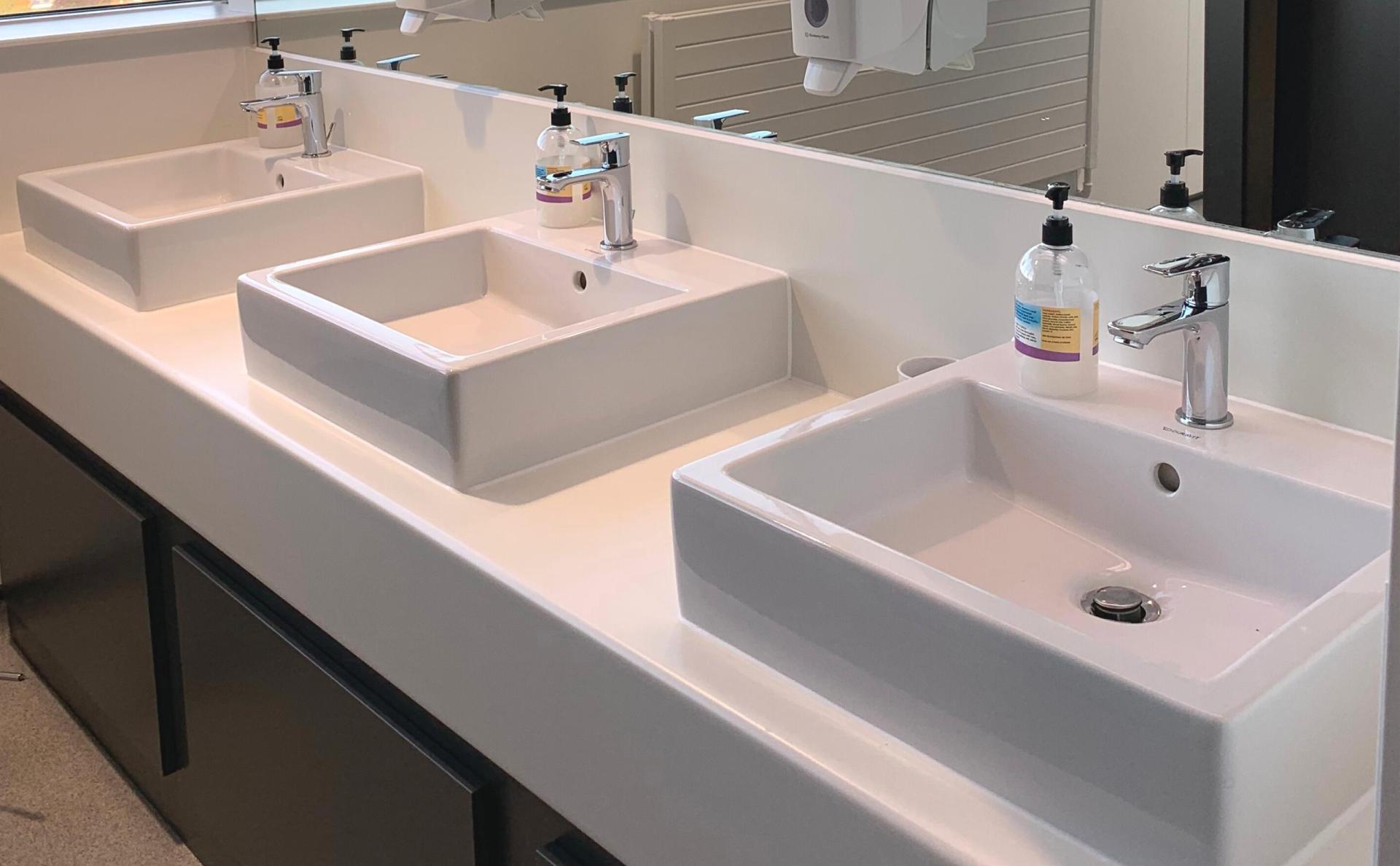 Modern washroom sinks with sleek designs, reflective surfaces, and amenities for a stylish hospitality venue experience.