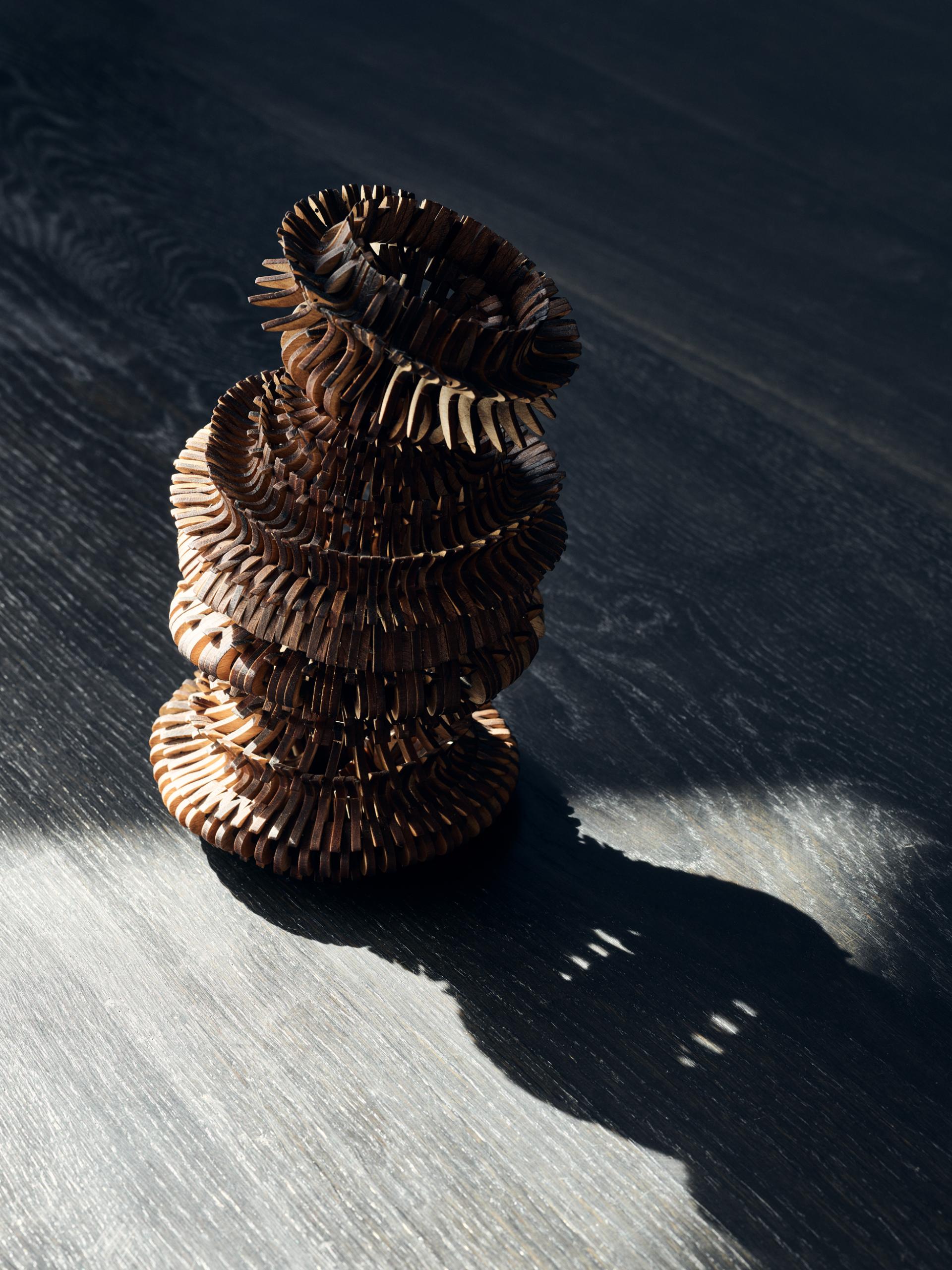 Intricate wooden sculpture casting a shadow, featured at the Collect exhibition at Somerset House.