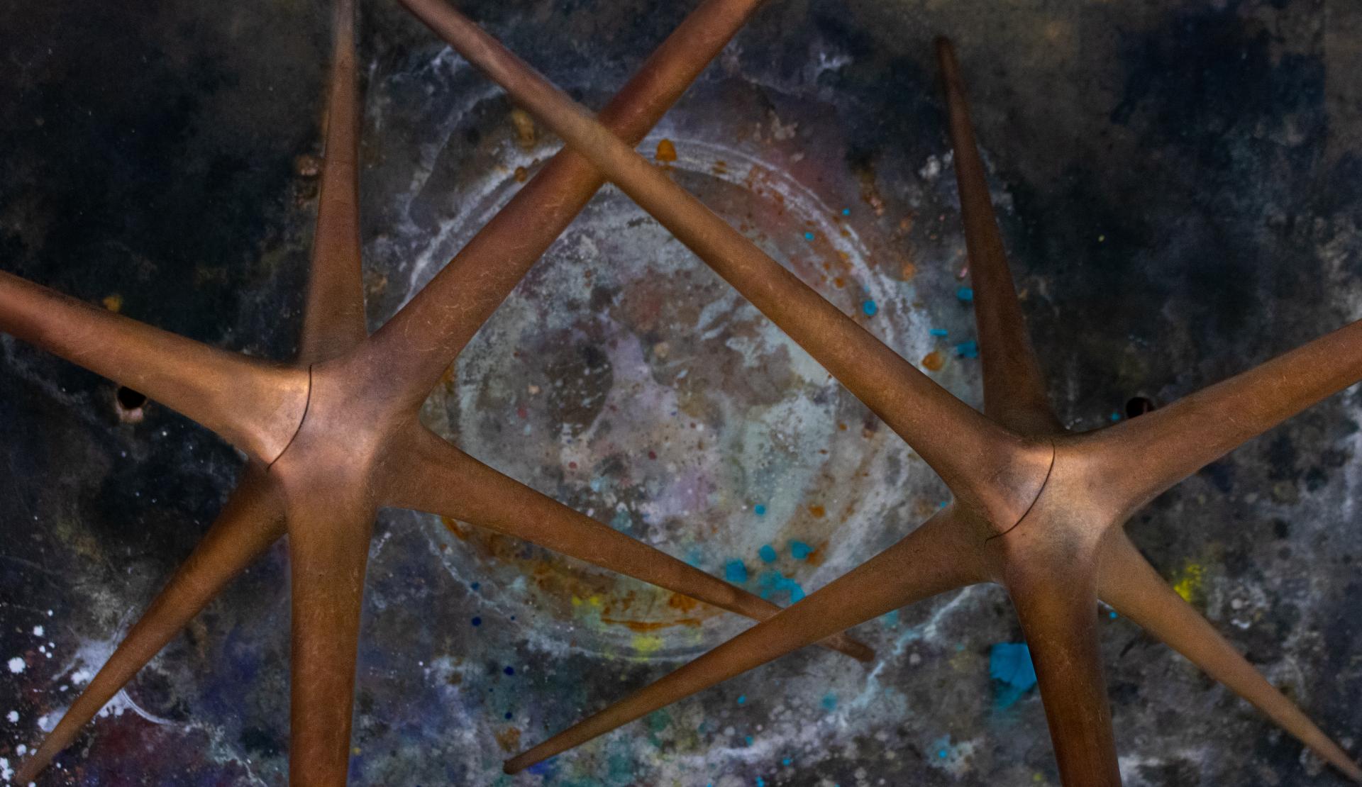 Brodie Neill's Supernova trestle design features intricate bronze legs set against a colorful, textured background.