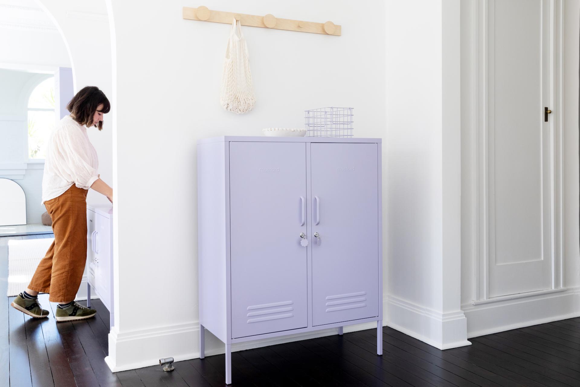 A woman in casual attire interacts with a playful purple locker cabinet in a stylish interior setting.