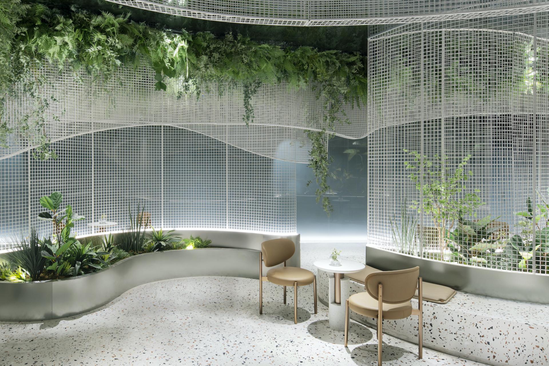 Elegant café interior featuring terrazzo flooring, curved seating, a mesh grid, and lush greenery design by Karv One.