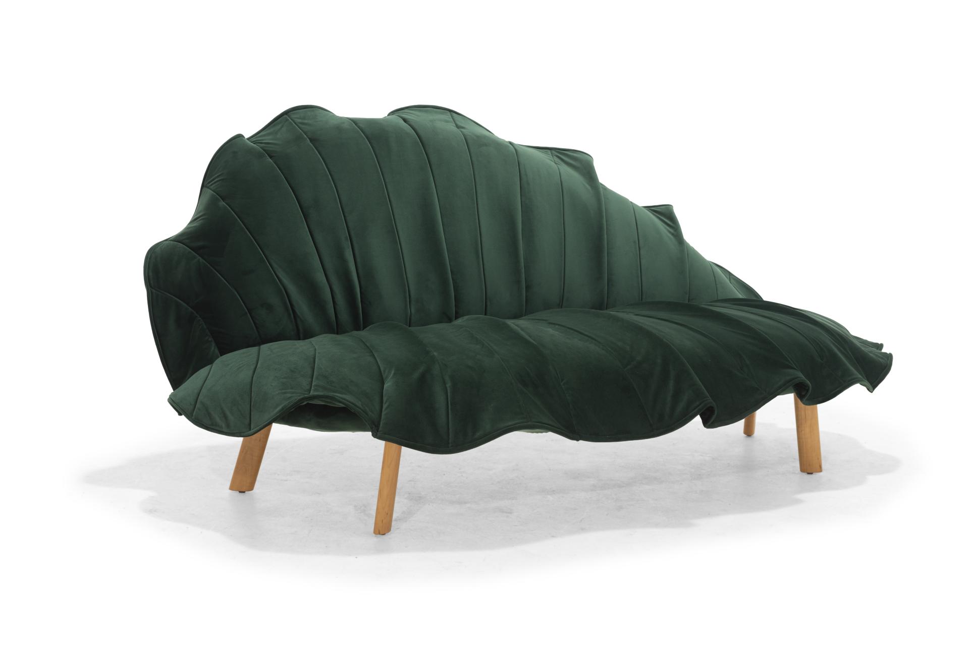 Stylish green leaf-shaped sofa designed by Kenneth Cobonpue, showcasing innovative upholstery and elegant wooden legs.