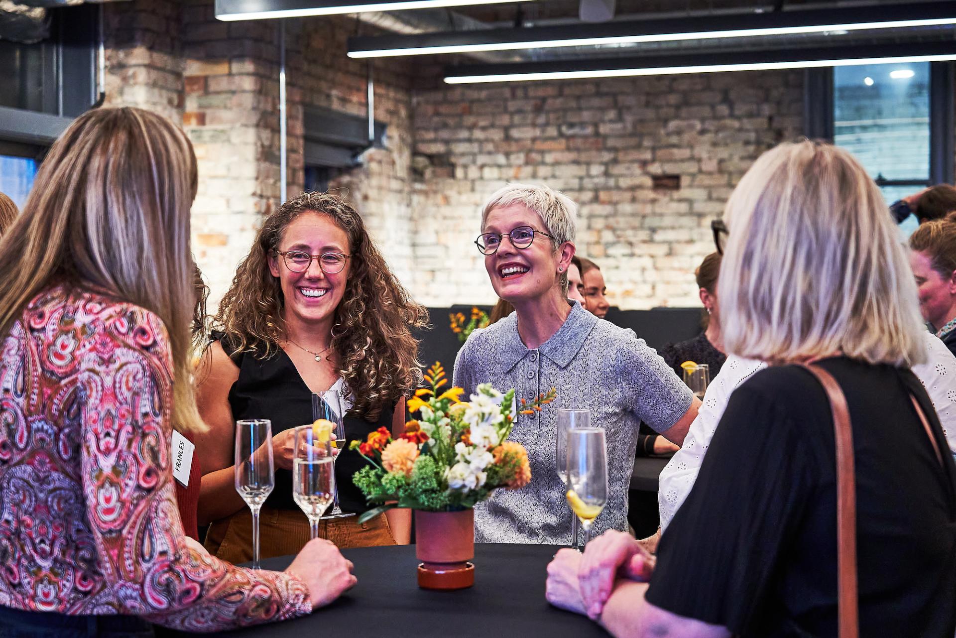 A group of women enjoying a lively conversation at a social event in Material Source Studio, Glasgow.