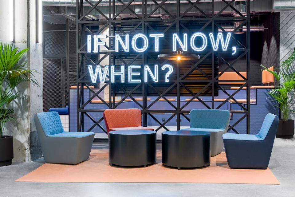 Modern co-living space featuring vibrant seating and a motivational neon sign at The Student Hotel in Barcelona.