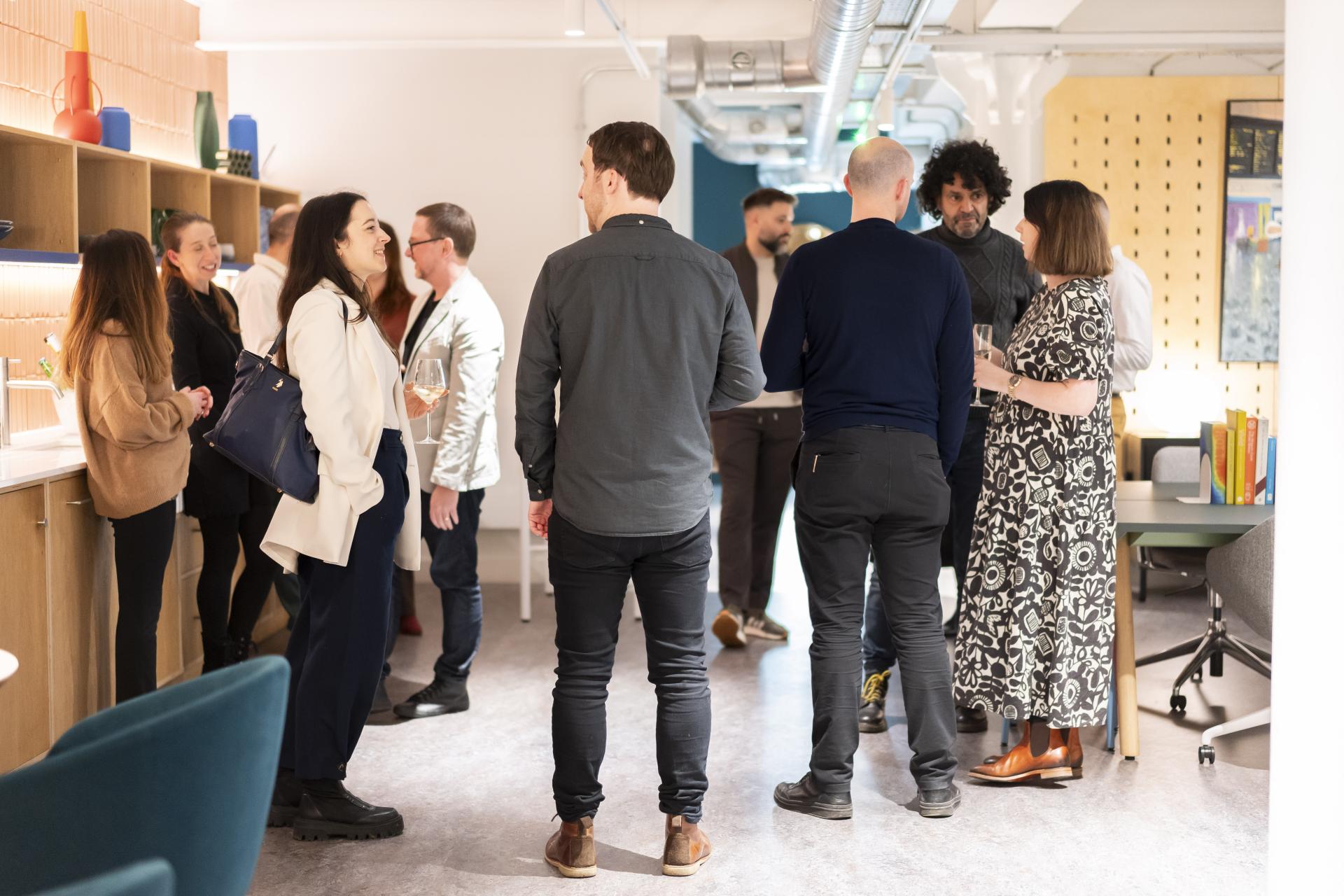 Professionals engaged in conversation during a networking event focused on technology and sustainability in design.