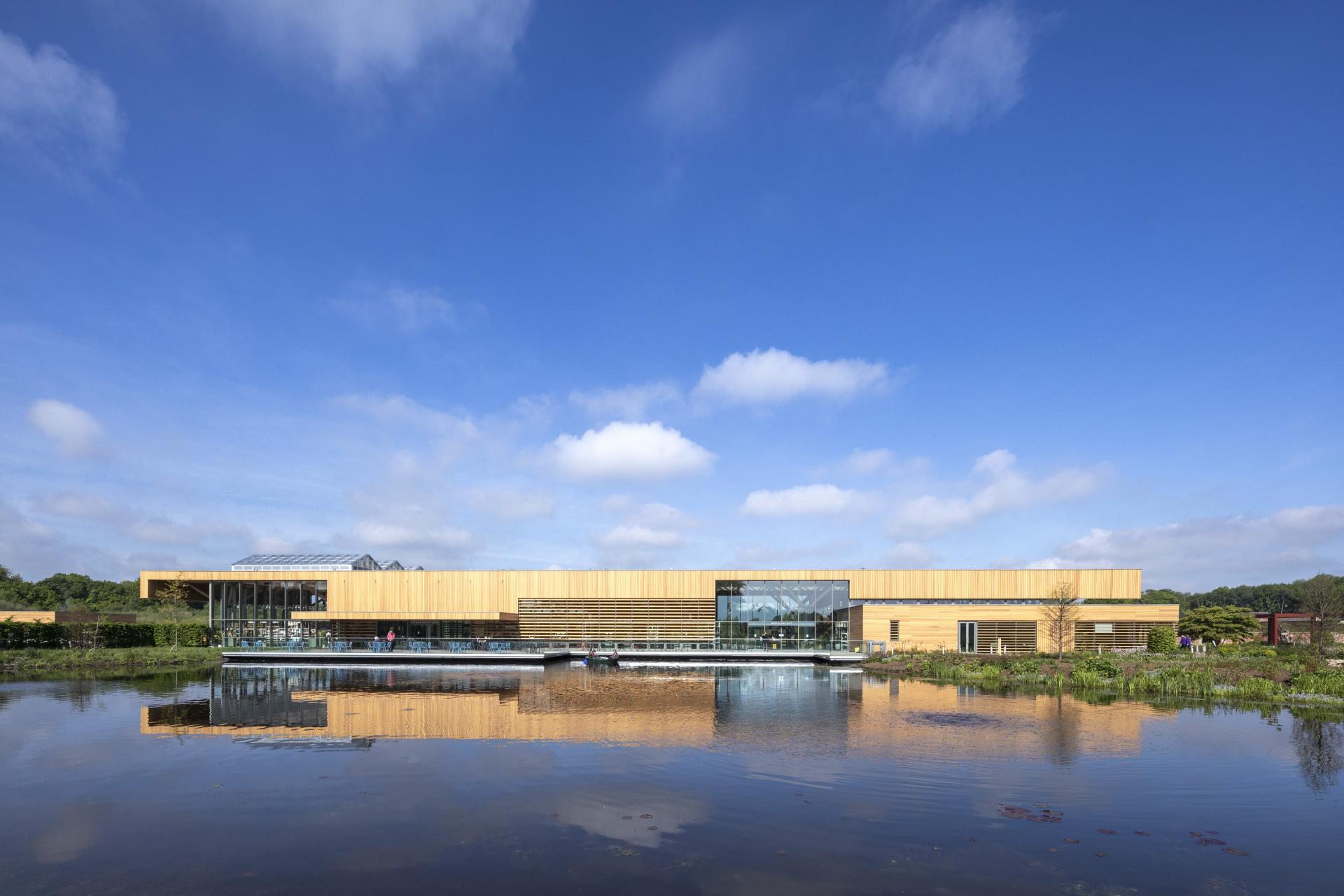 Modern wooden building reflected in calm water, showcasing sustainable architecture nominated for the Wood Awards 2021.