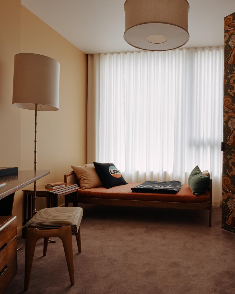 Elegant interior featuring a cozy daybed, stylish lamp, and warm color palette designed by Bella Freud and Maria Speake.