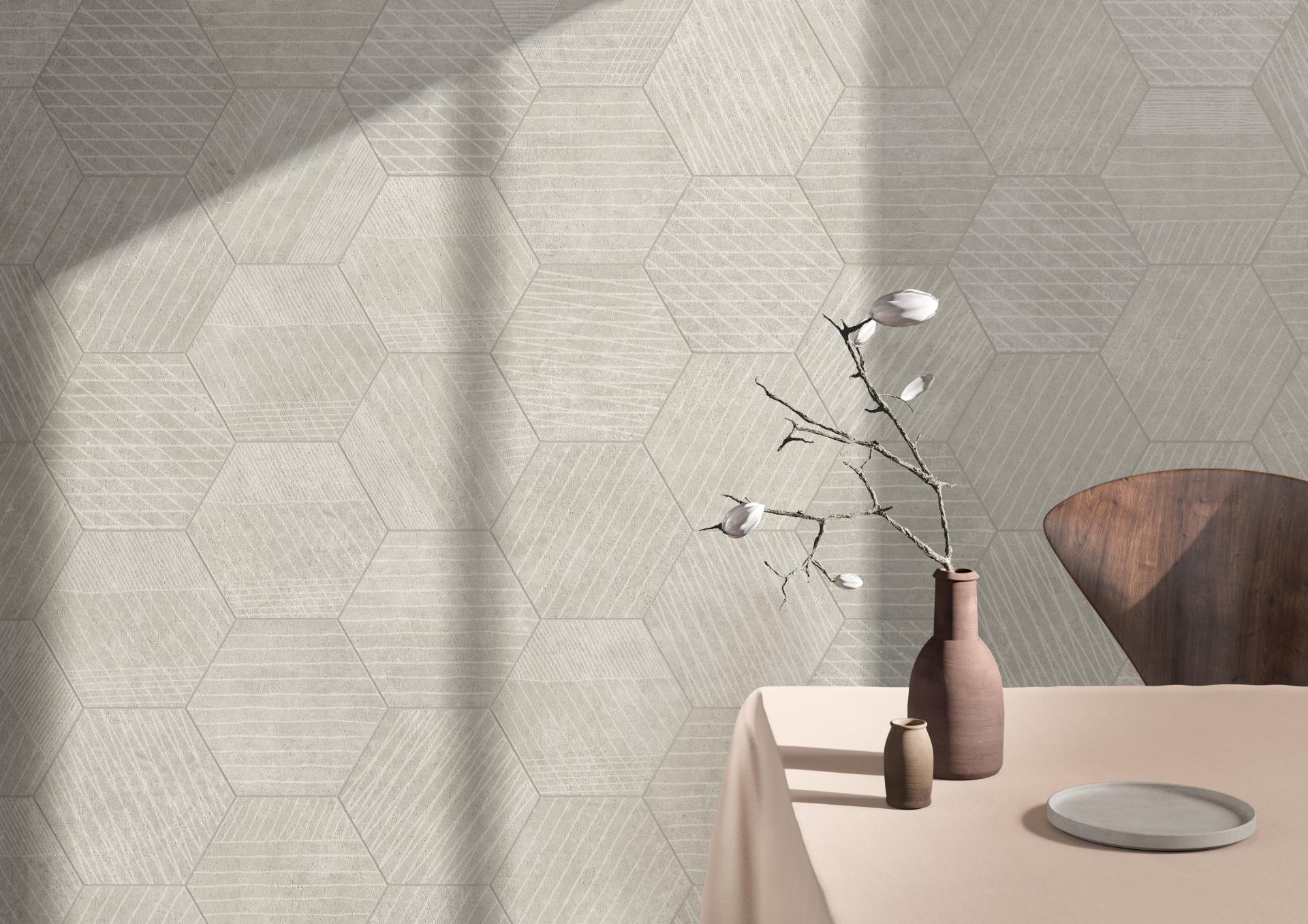 Textured hexagonal tiles in neutral tones decorate a wall, complemented by modern vases and a wooden chair.