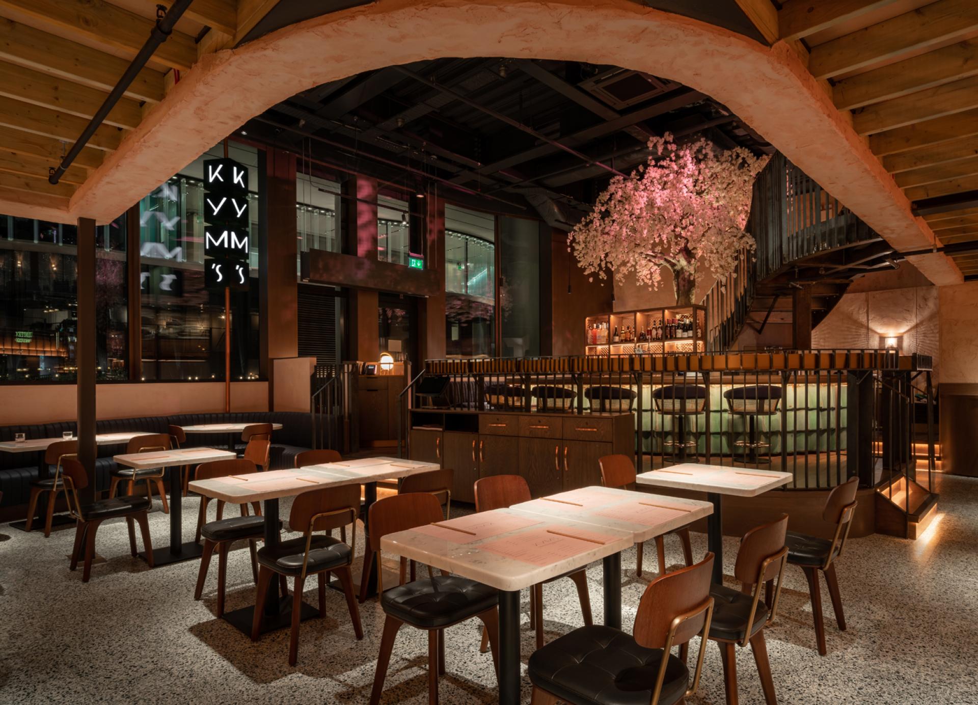 Elegant interior of Chef Andrew Wong's new restaurant featuring marble tables, wooden chairs, and a cherry blossom tree.