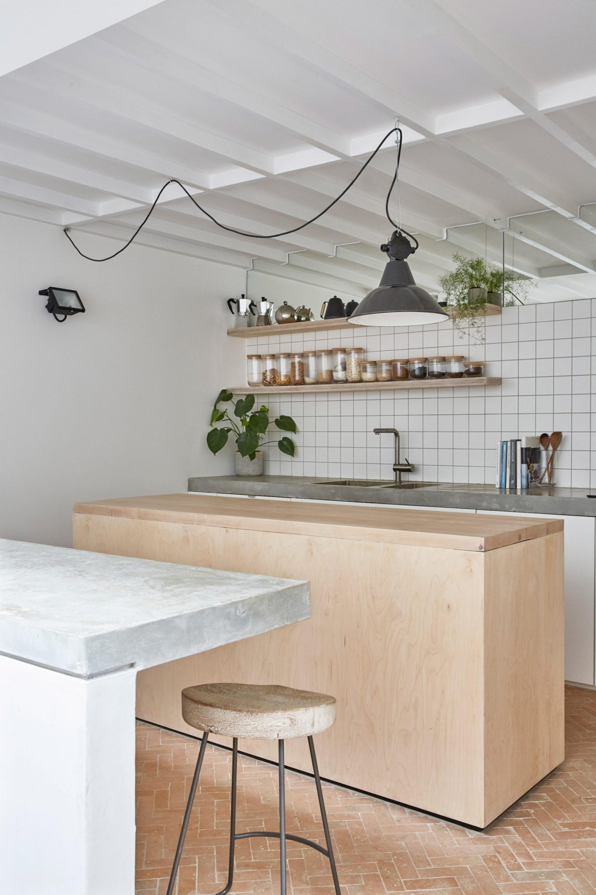 Modern kitchen with light wood cabinetry, concrete countertops, open shelving, and natural elements in a calm Hackney mews house.