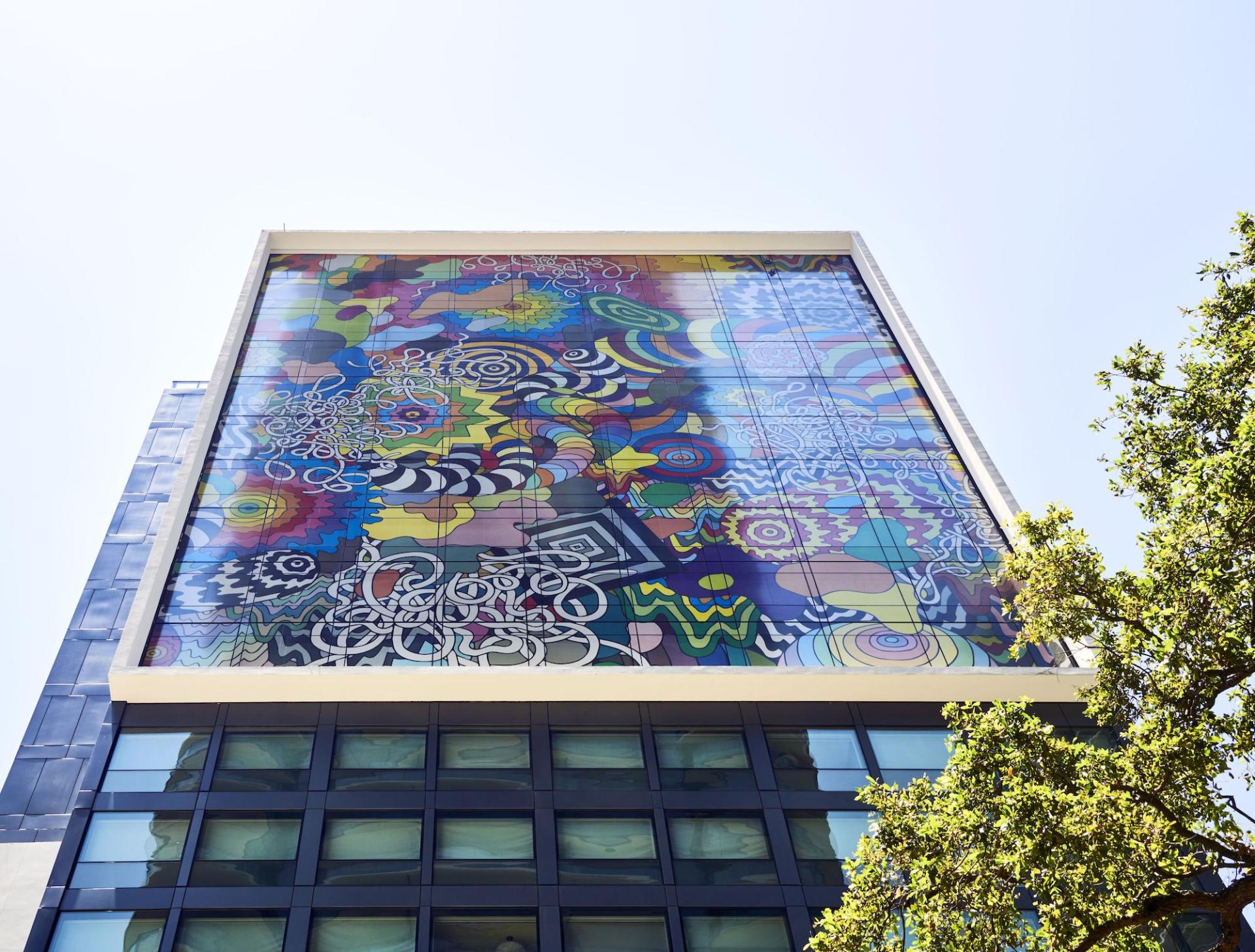 Vibrant mural adorning the citizenM hotel building in Miami, showcasing colorful abstract designs against a blue sky.