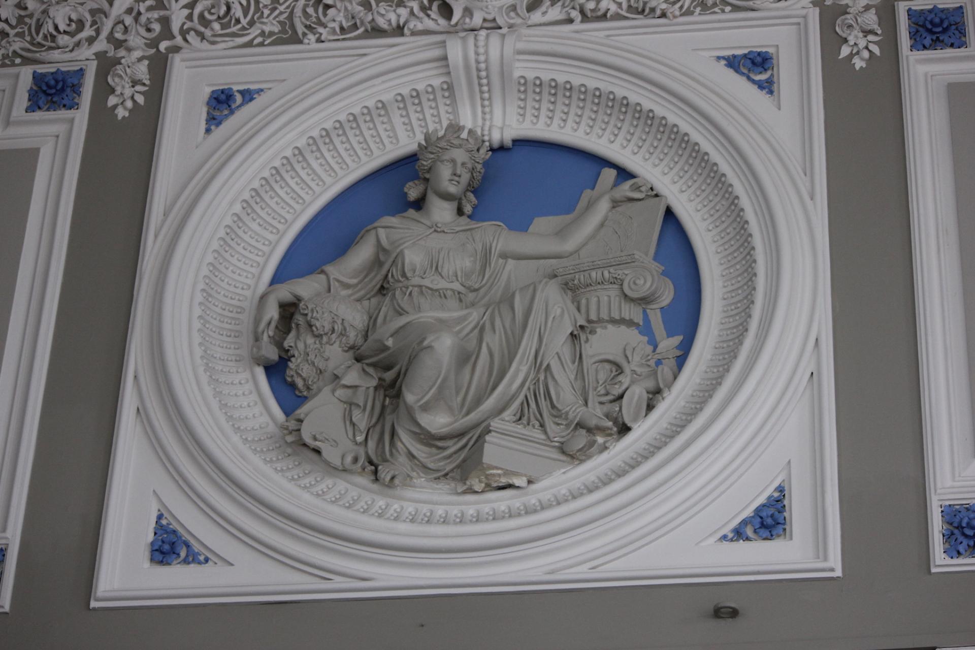 Intricate plasterwork in Todmorden Town Hall's ballroom, showcasing a classical figure against a blue background.