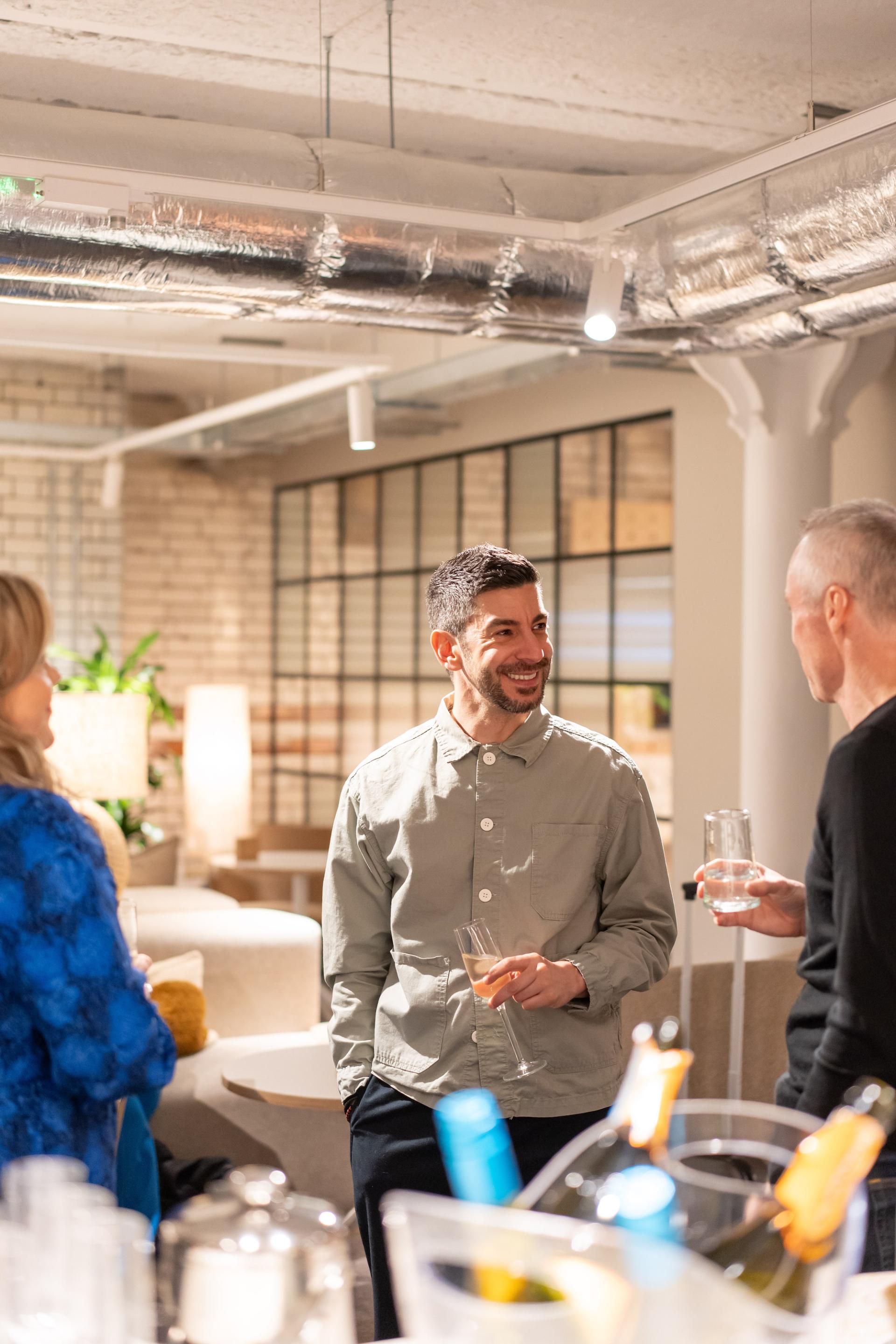 Participants engage in discussion at a seminar on sustainability and value engineering, enjoying drinks in a modern setting.