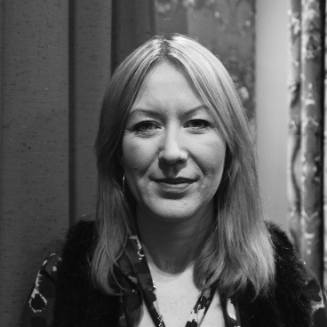 Kirsty Neil, Senior Designer at Bute, poses against a backdrop of textured fabric, showcasing her creative style and design expertise.