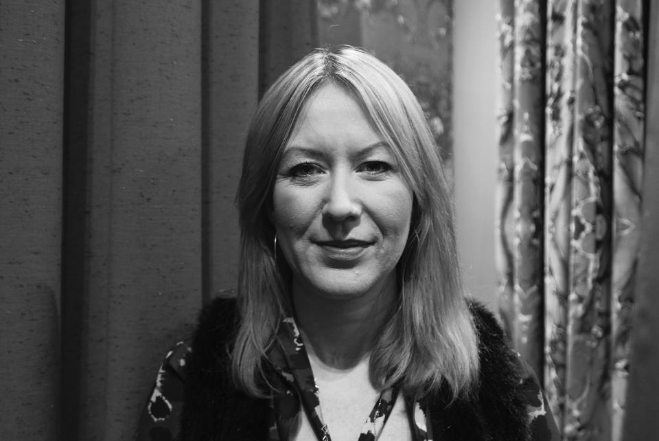 Kirsty Neil, Senior Designer at Bute, poses against a backdrop of textured fabric, showcasing her creative style and design expertise.