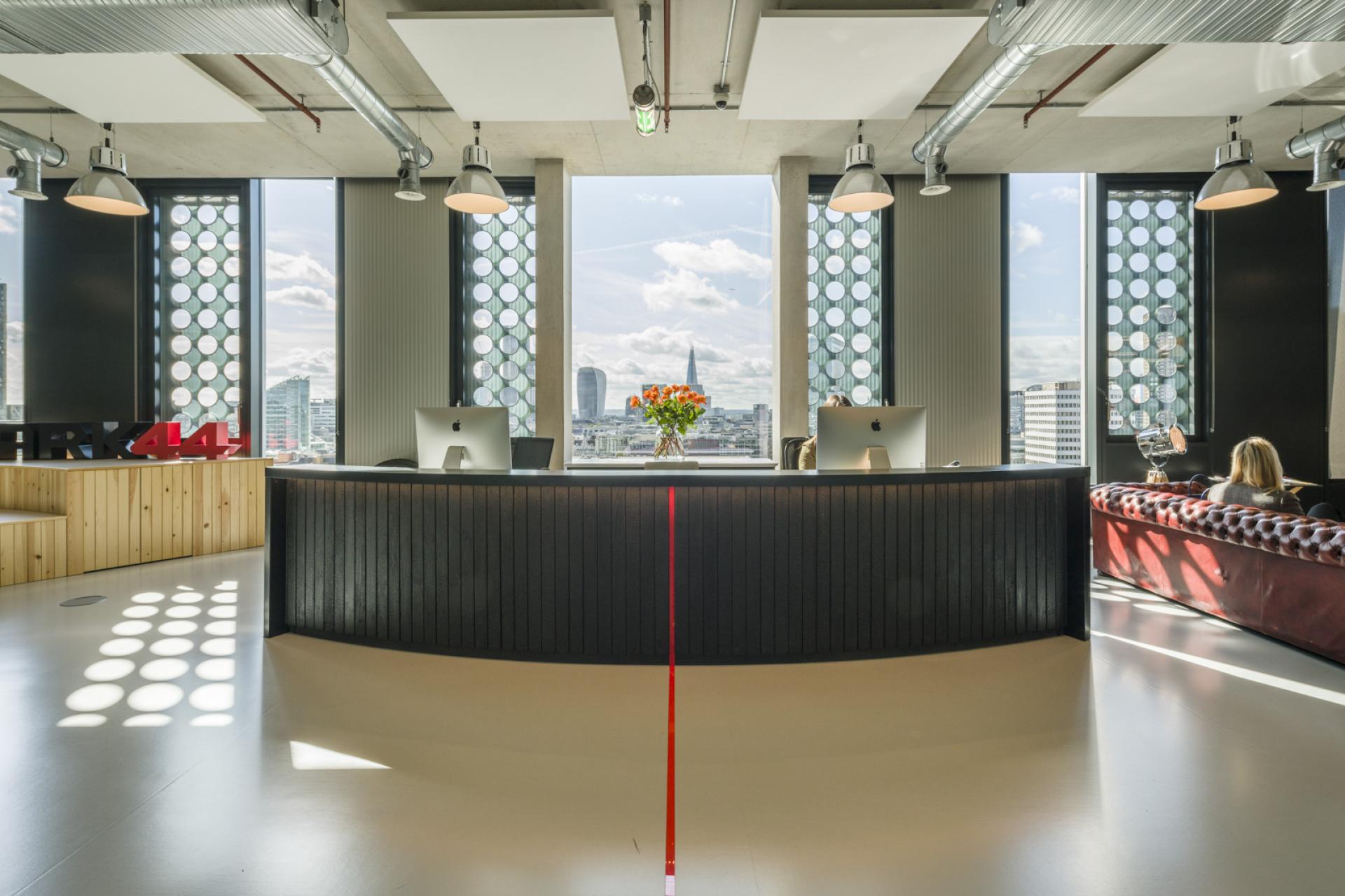 Modern office reception area featuring sleek design, large windows, and creative workspace, embodying playful interior architecture.