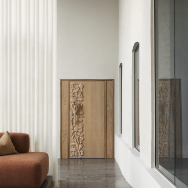 Modern interior featuring an elegant wooden cabinet with carved floral design and textured curtains, enhancing Scandinavian design aesthetics.