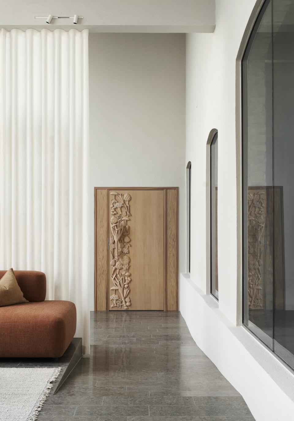 Modern interior featuring an elegant wooden cabinet with carved floral design and textured curtains, enhancing Scandinavian design aesthetics.