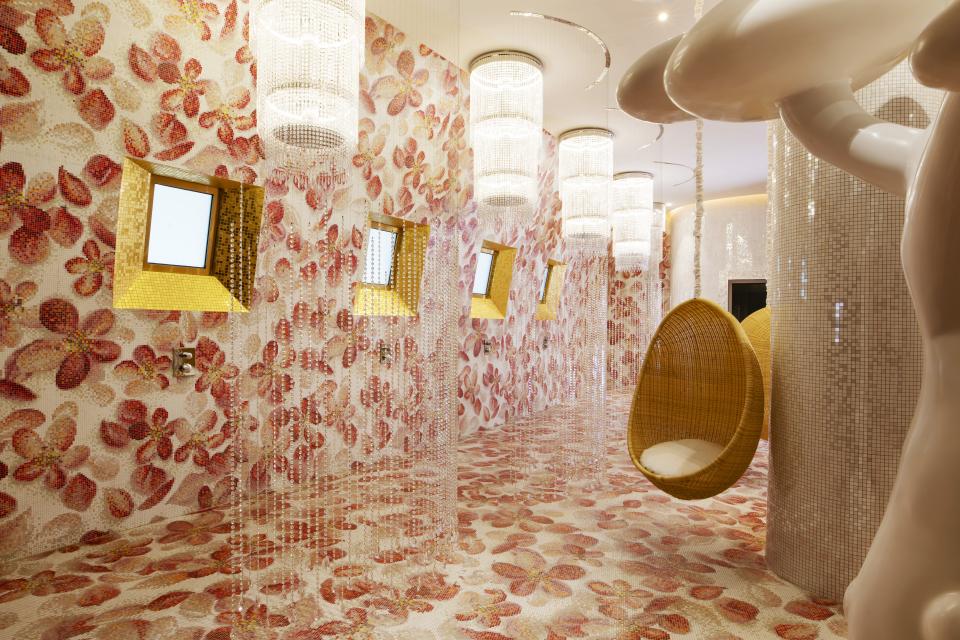 Luxurious restroom interior at Mondrian Doha featuring floral mosaics, unique lighting, and a suspended hanging chair.