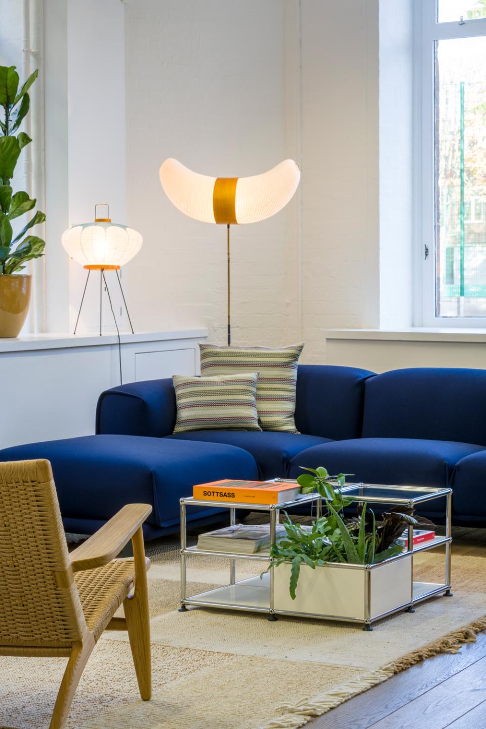 Stylish modular furniture in USM's Clerkenwell showroom, featuring a blue sofa, decorative plants, and unique lighting.