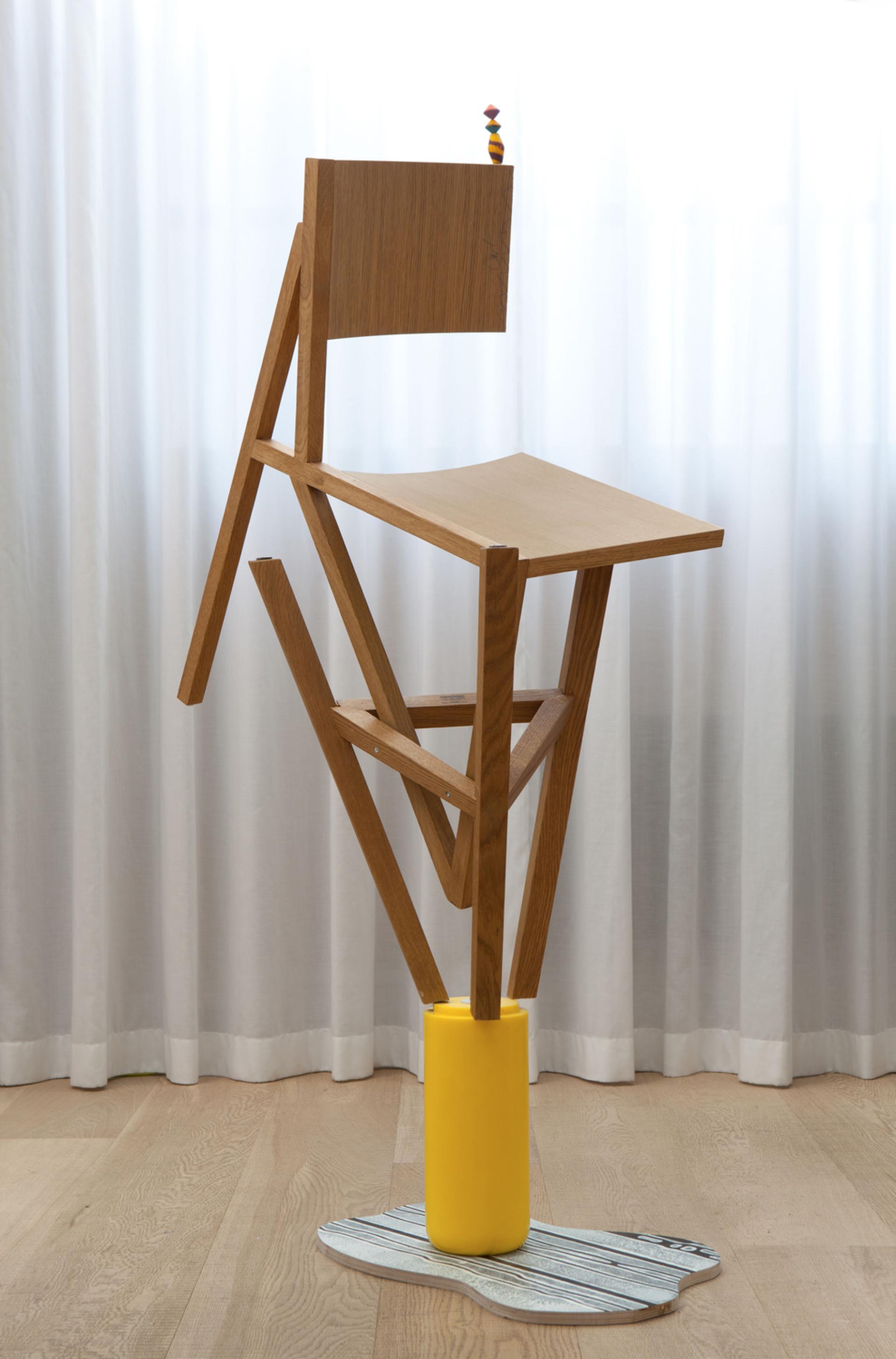 Innovative wooden chair designed by Lorenzo Vitturi, balancing on a bright yellow base and abstract platform, highlighting contemporary art in furniture.