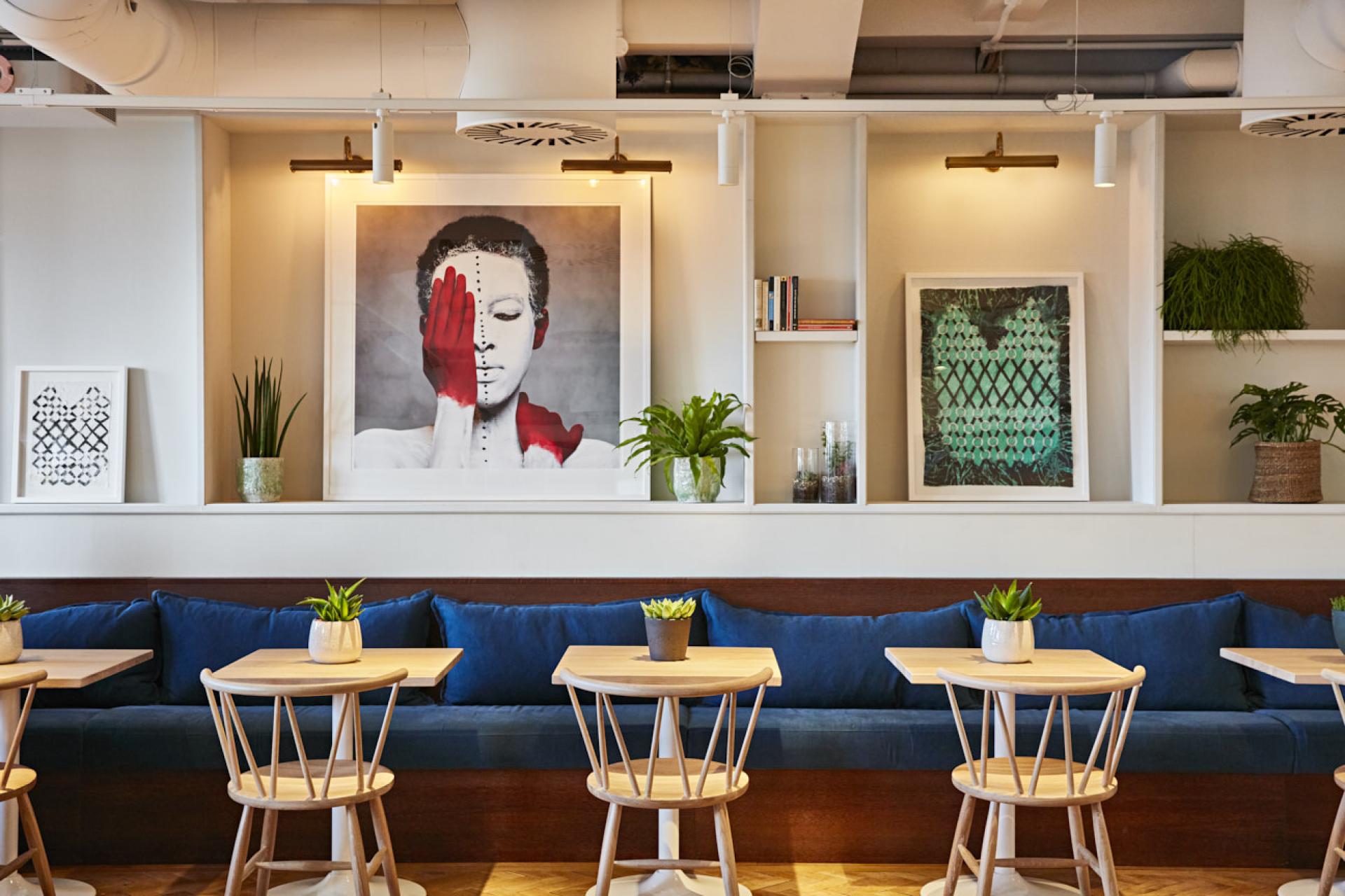 Stylish interior of The Conduit Members Club featuring contemporary art, plants, and cozy seating in Scandinavian-African design.