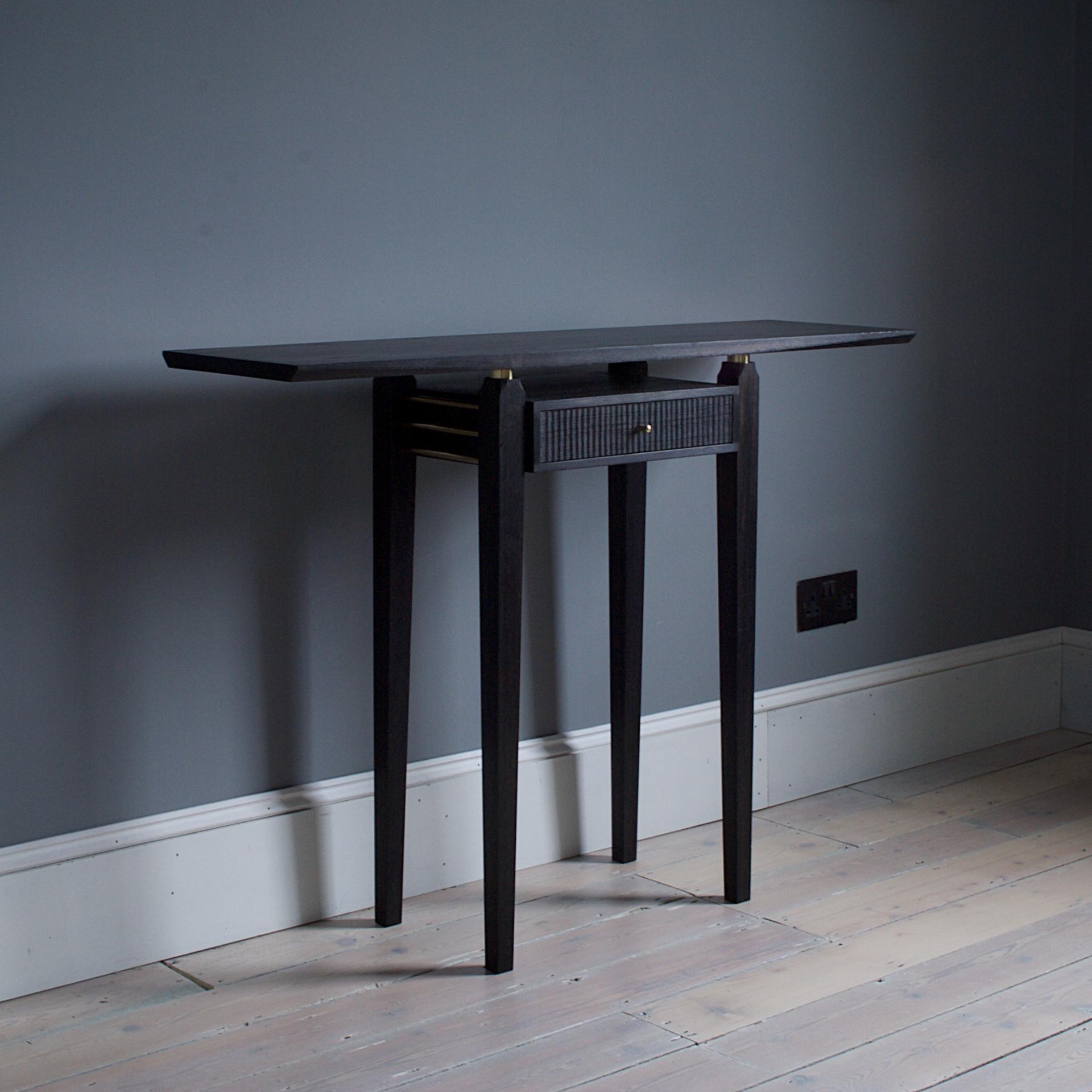 Sleek contemporary black table with drawer, highlighting craftsmanship and material sustainability in modern furniture design.