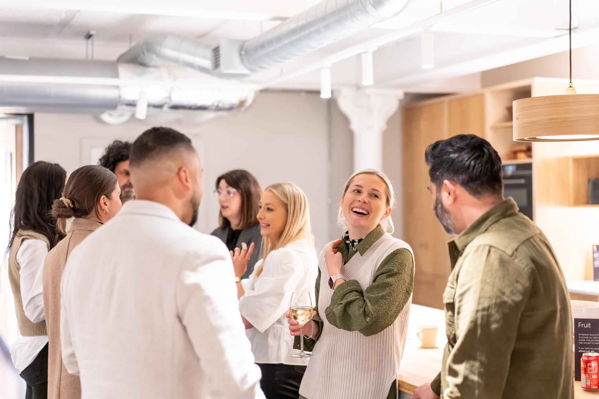 Group of diverse professionals discussing EDI concepts and culture in a modern workspace setting, fostering collaboration and connection.