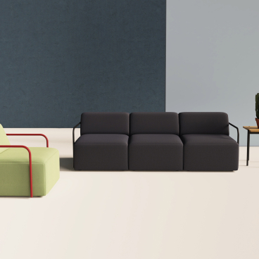 Modern furniture arrangement featuring a green chair with red accents, a dark sofa, and a potted plant.