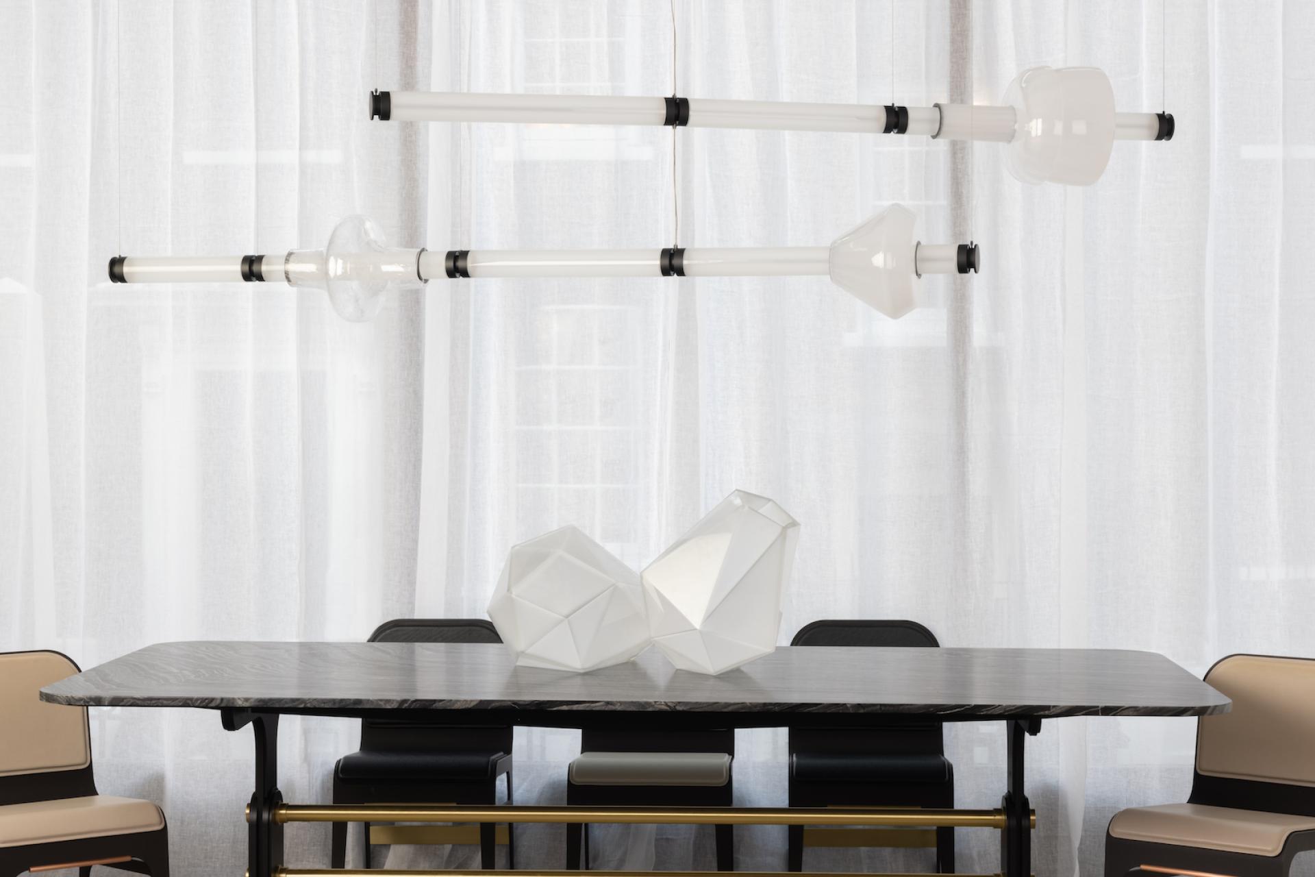 Luna Kaleido lighting collection showcased above a modern dining table with sculptural decor in an elegant interior setting.