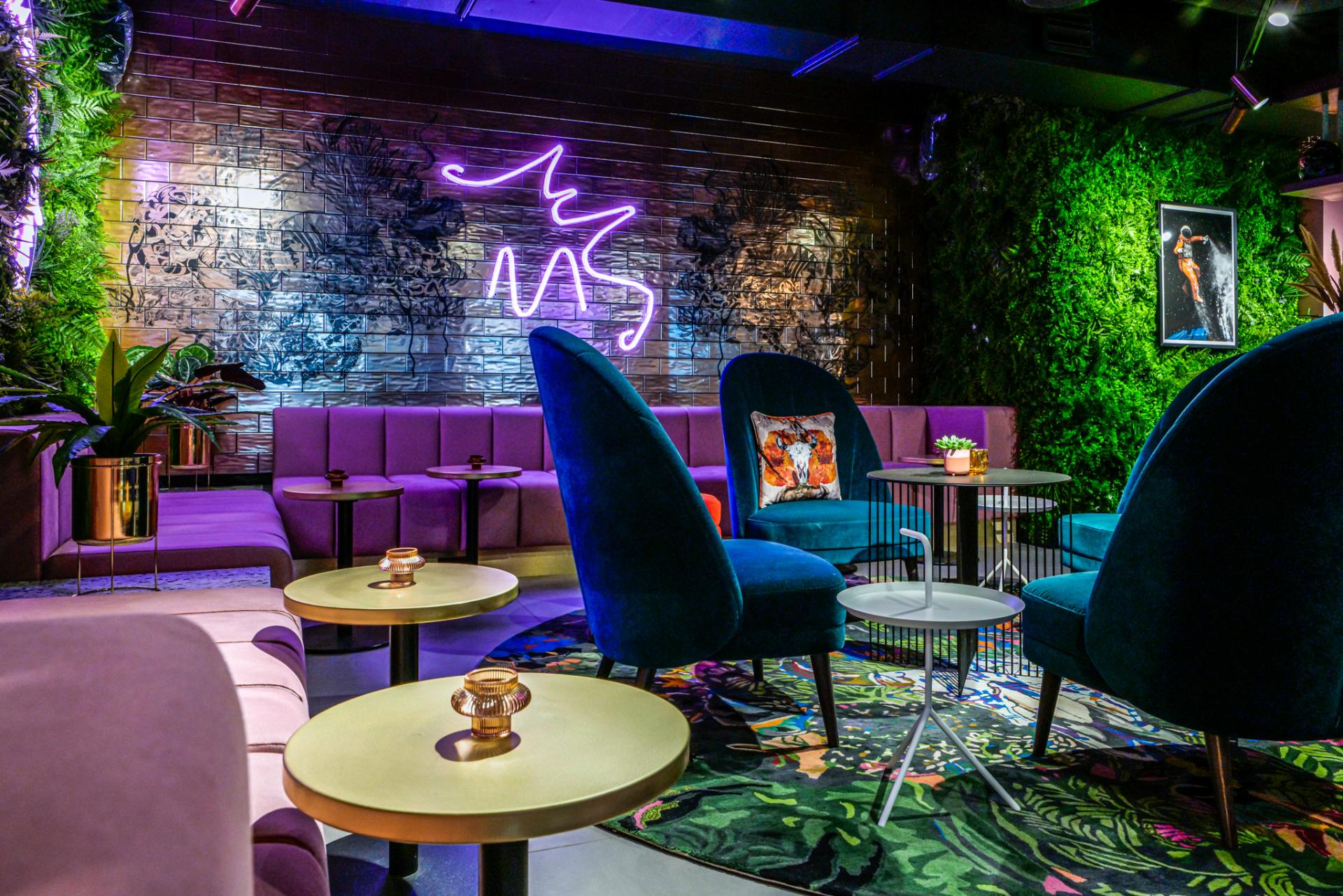 Vibrant lounge area at Manchester's Qbic hotel, featuring bold green plants, plush seating, and artistic decor.