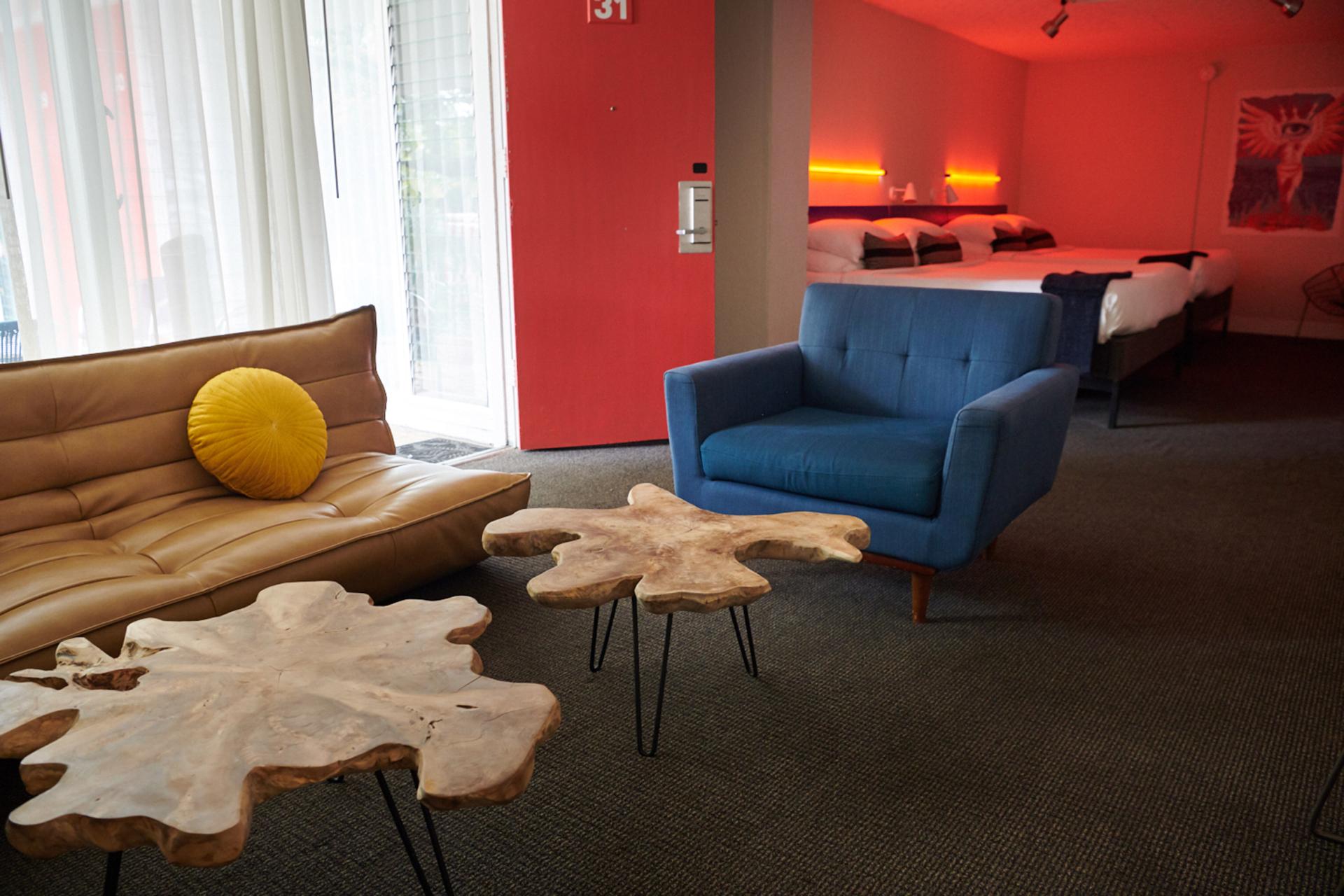 Stylish hotel room at the Phoenix Hotel featuring a modern sofa, blue armchair, and unique wooden coffee tables.