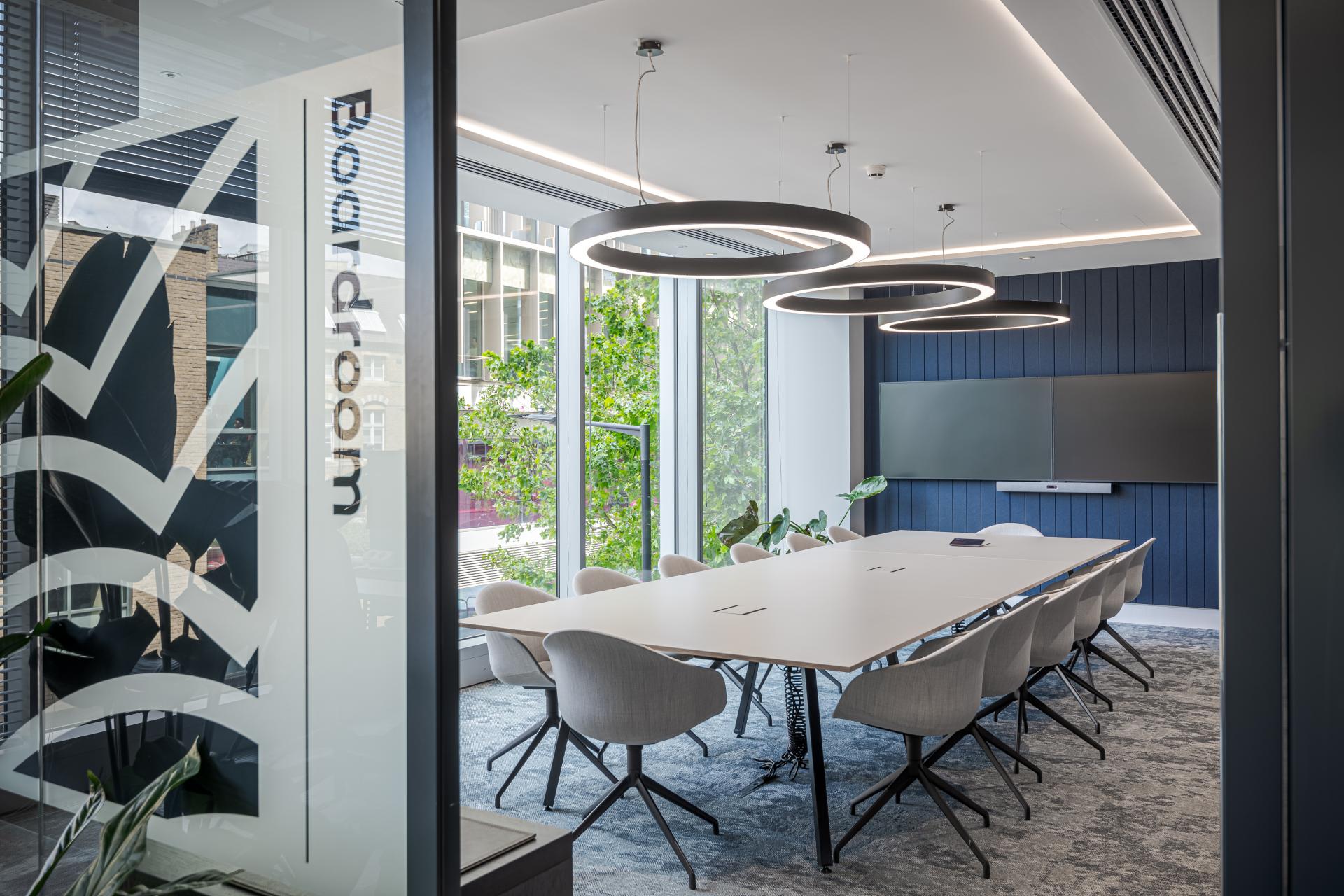 Modern boardroom design featuring a long table, light fixtures, and greenery, enhancing collaboration and community at Landsec's headquarters.