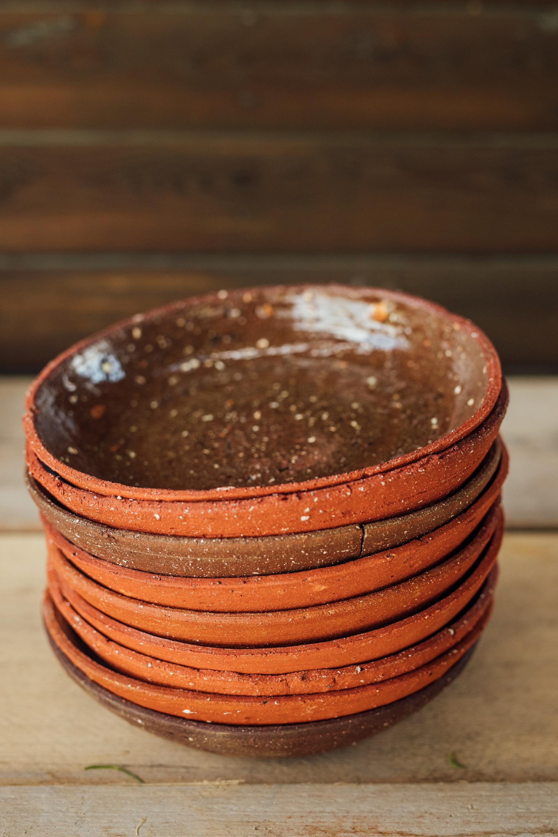 Stacked handmade clay bowls showcasing earthy colors, highlighting artisan craftsmanship in the maker in residence program at Bruno Schooling.