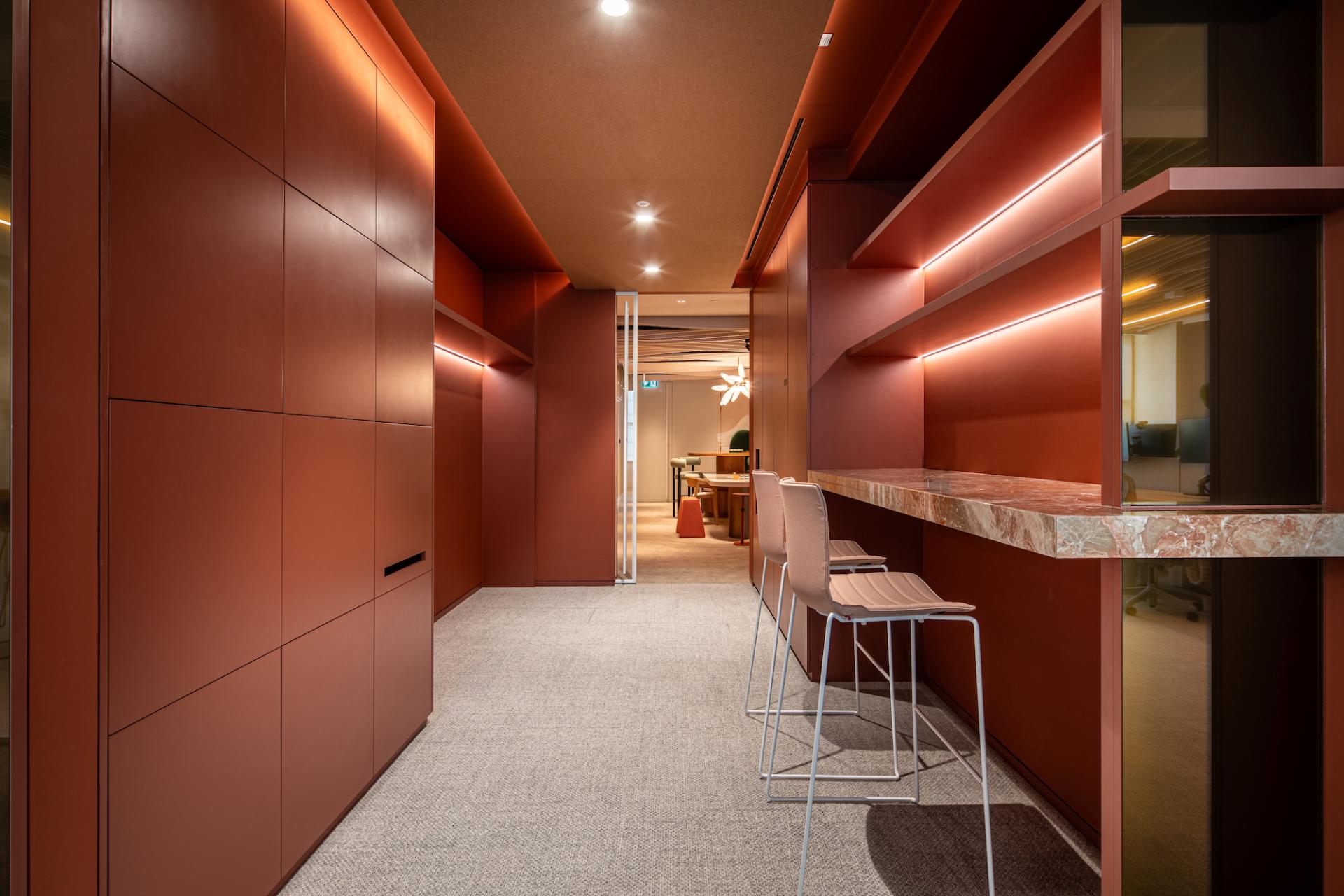 Modern office interior featuring warm earthy tones, minimalist design, and a stylish workspace with chairs and a bar counter.