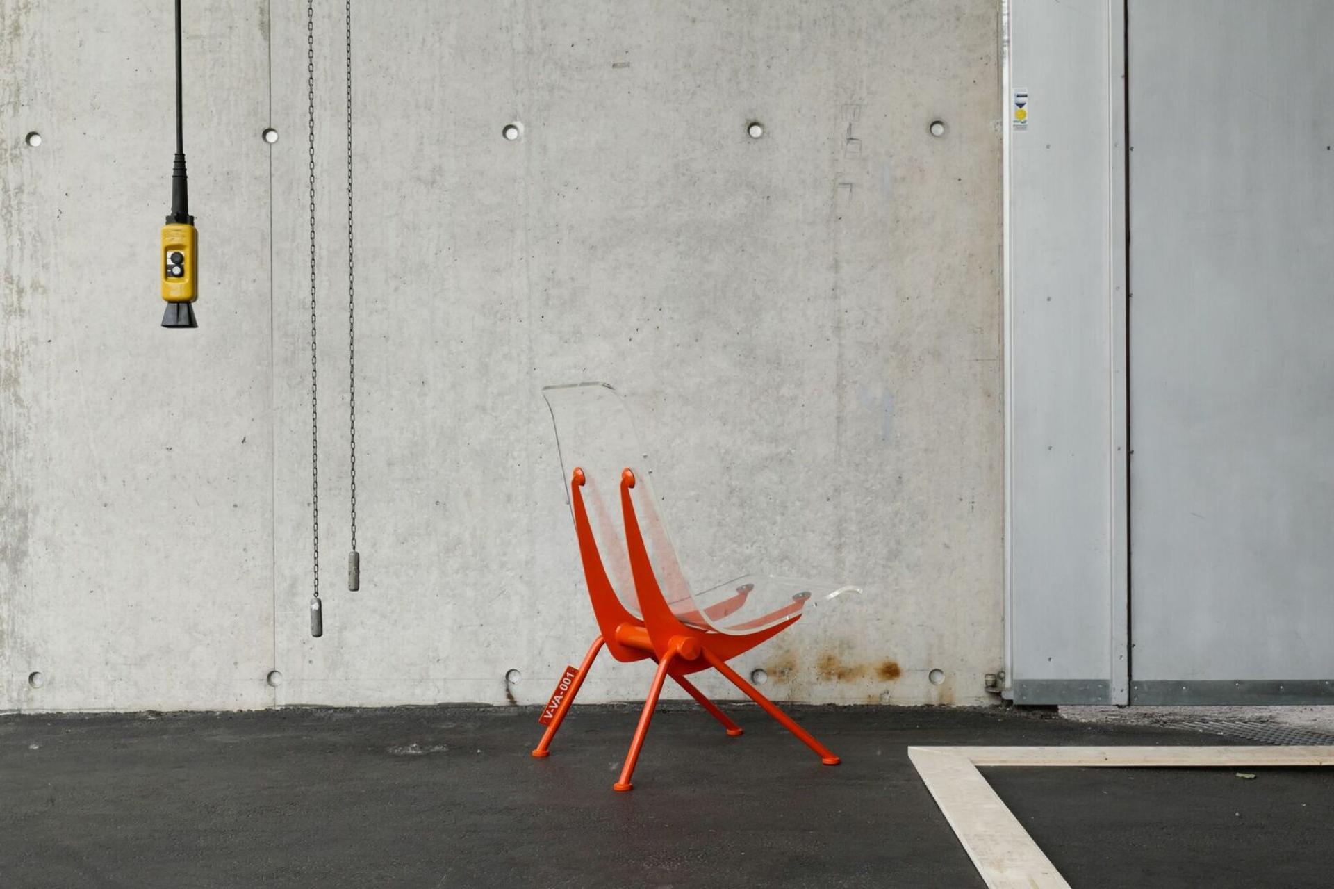 Futuristic orange chair designed by Virgil Abloh for Vitra, set against a concrete backdrop with industrial elements.