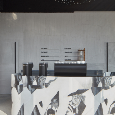 Minimalist coffee bar design at Drop Coffee's Abu Dhabi location, featuring textured surfaces and modern monochrome decor.
