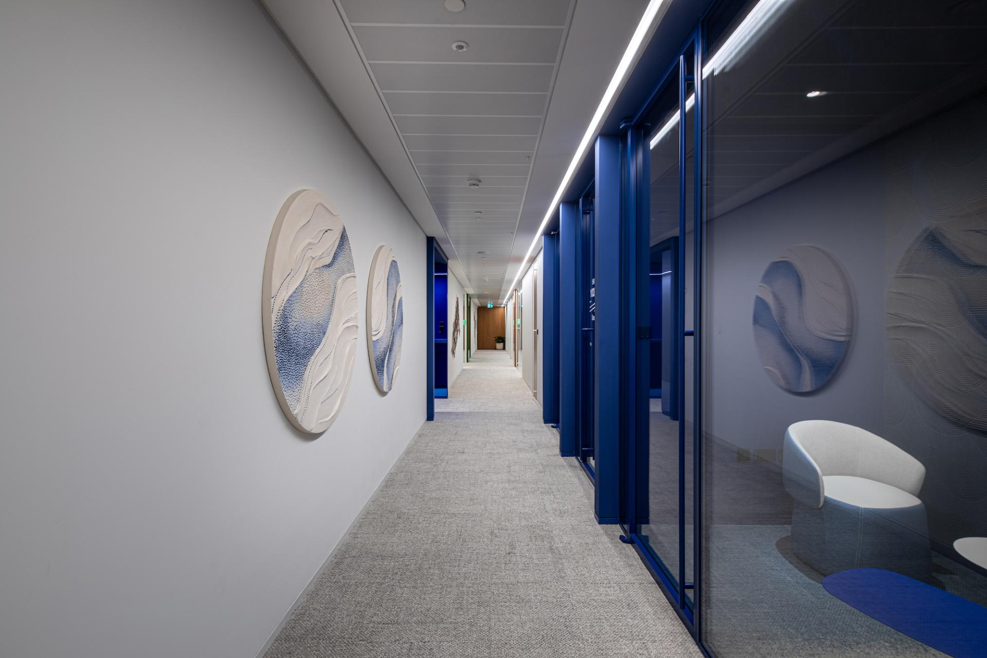 Brightly colored hallway in a modern Dubai workplace, featuring abstract wall art and glass meeting rooms.